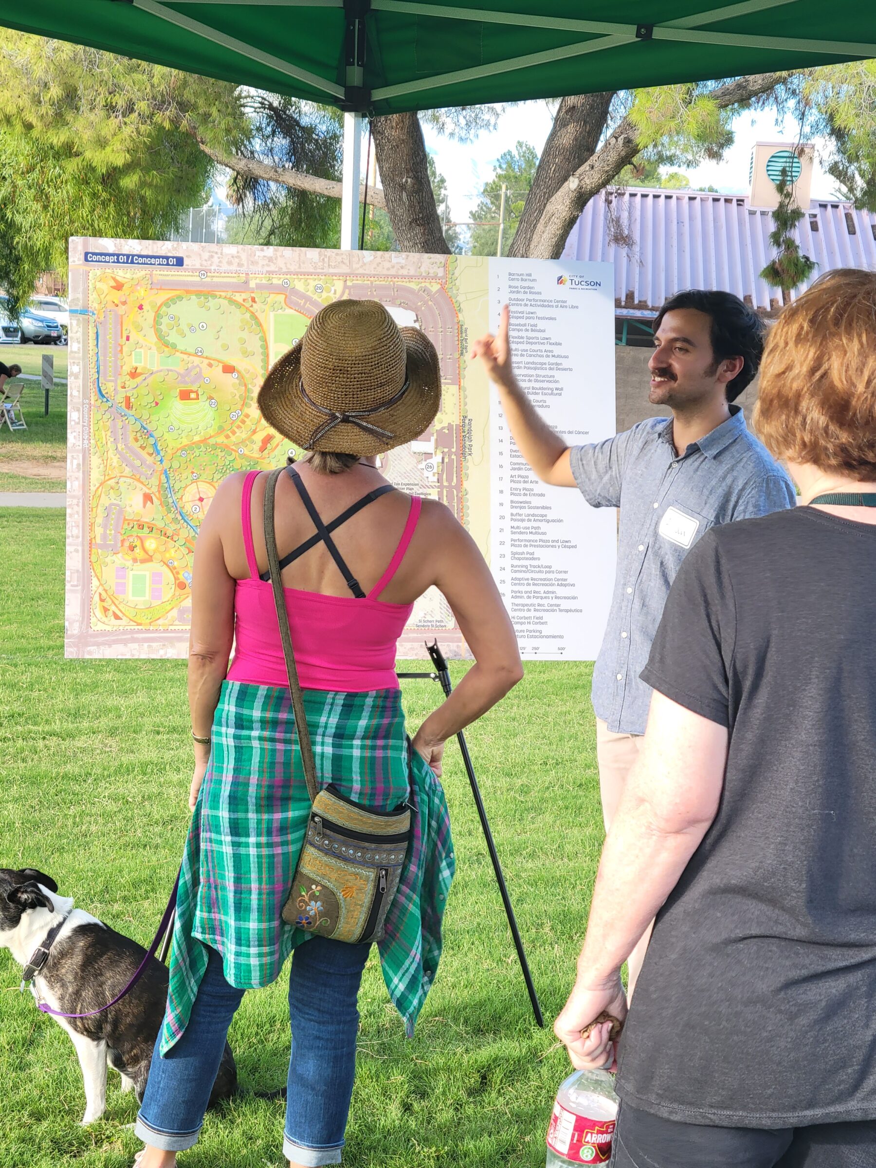 Design team member showing board with illustrated site plan to community members