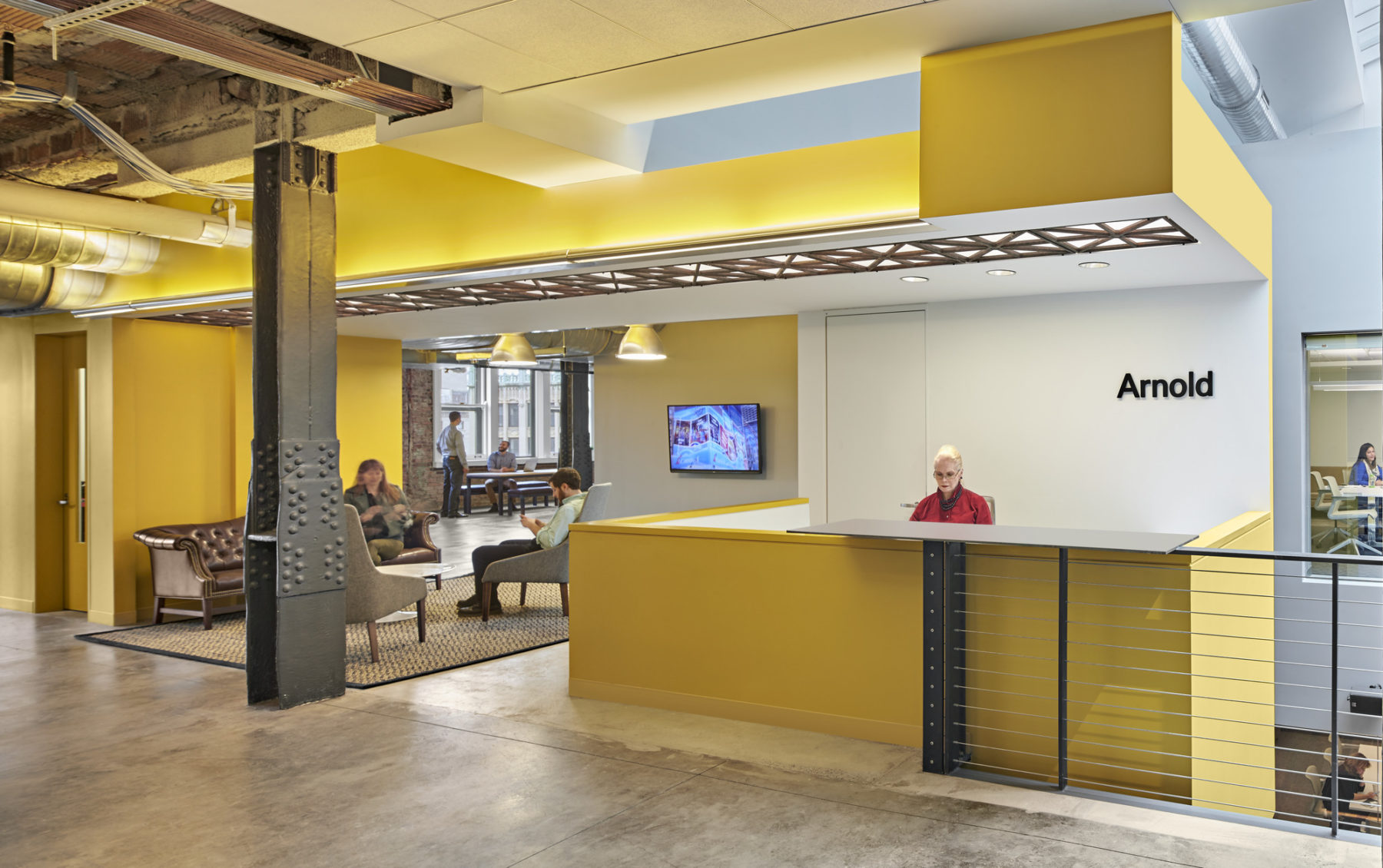 Receptionist sitting behind yellow reception desk at Havas-Arnold Worldwide Boston Headquarters