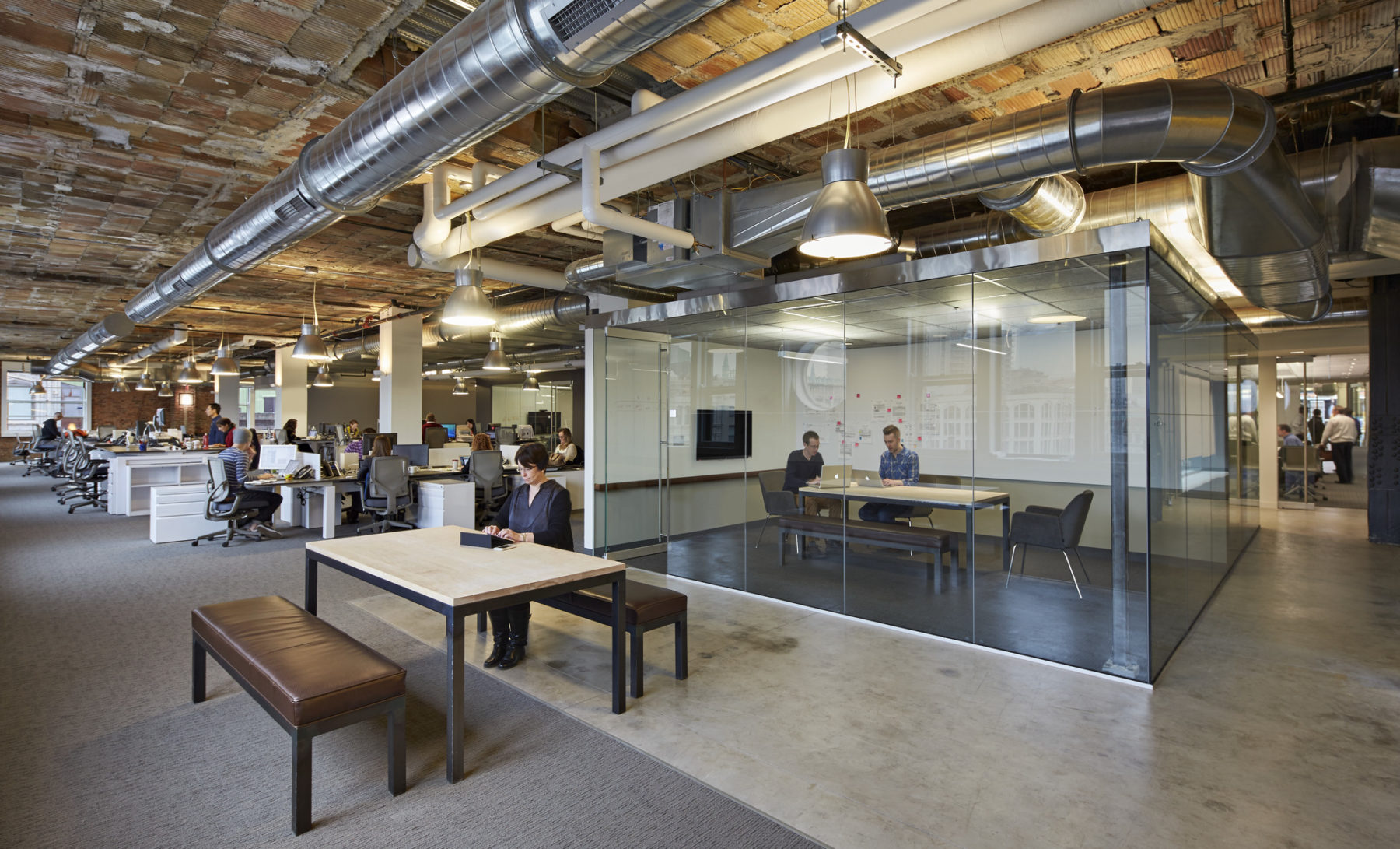 Woman working at a wooden table in an open office environment