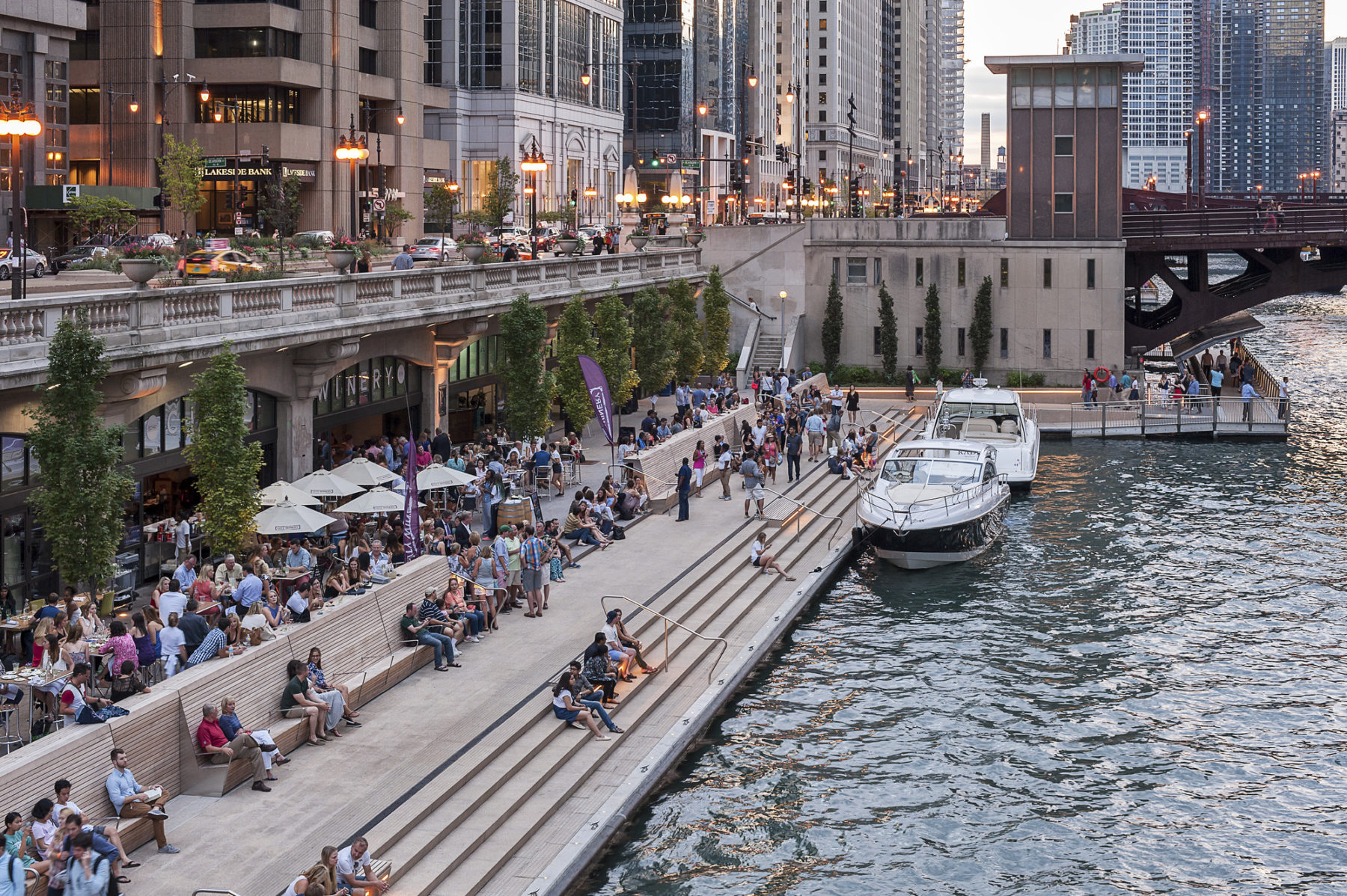 people sit on steps beside a river