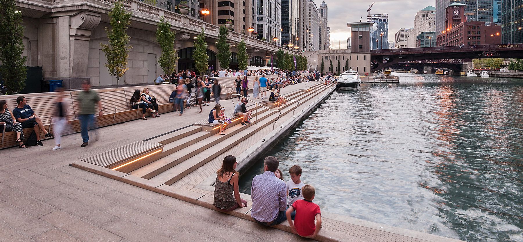 people sitting on steps near a river