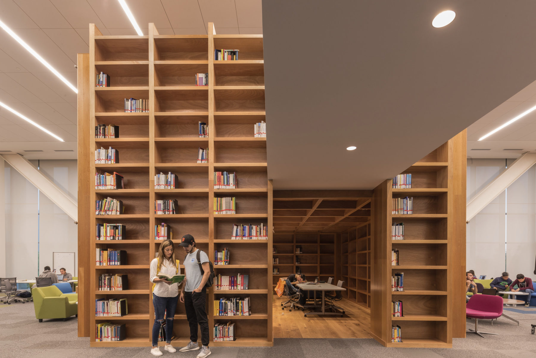 two people stand in front of a large bookshelf