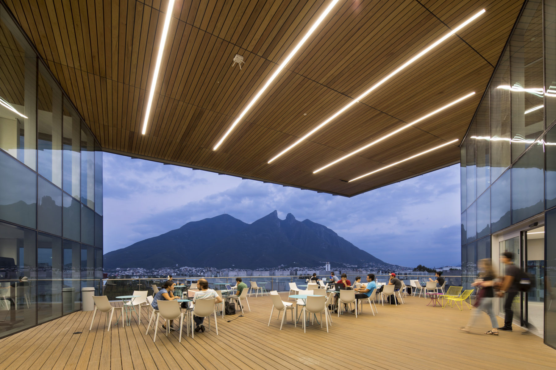 People sitting at tables, a mountain in the background