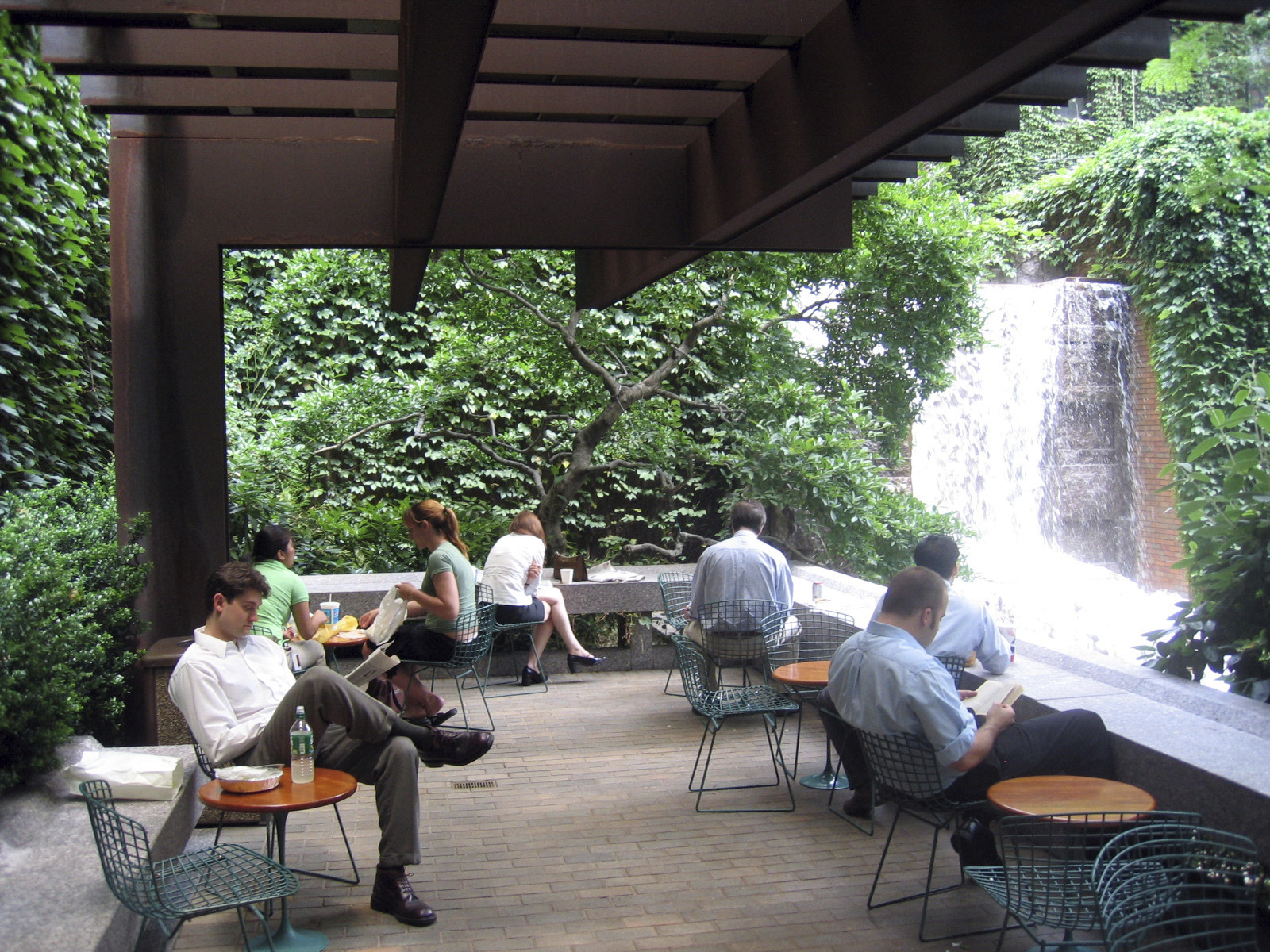 people sitting at tables near a waterfall