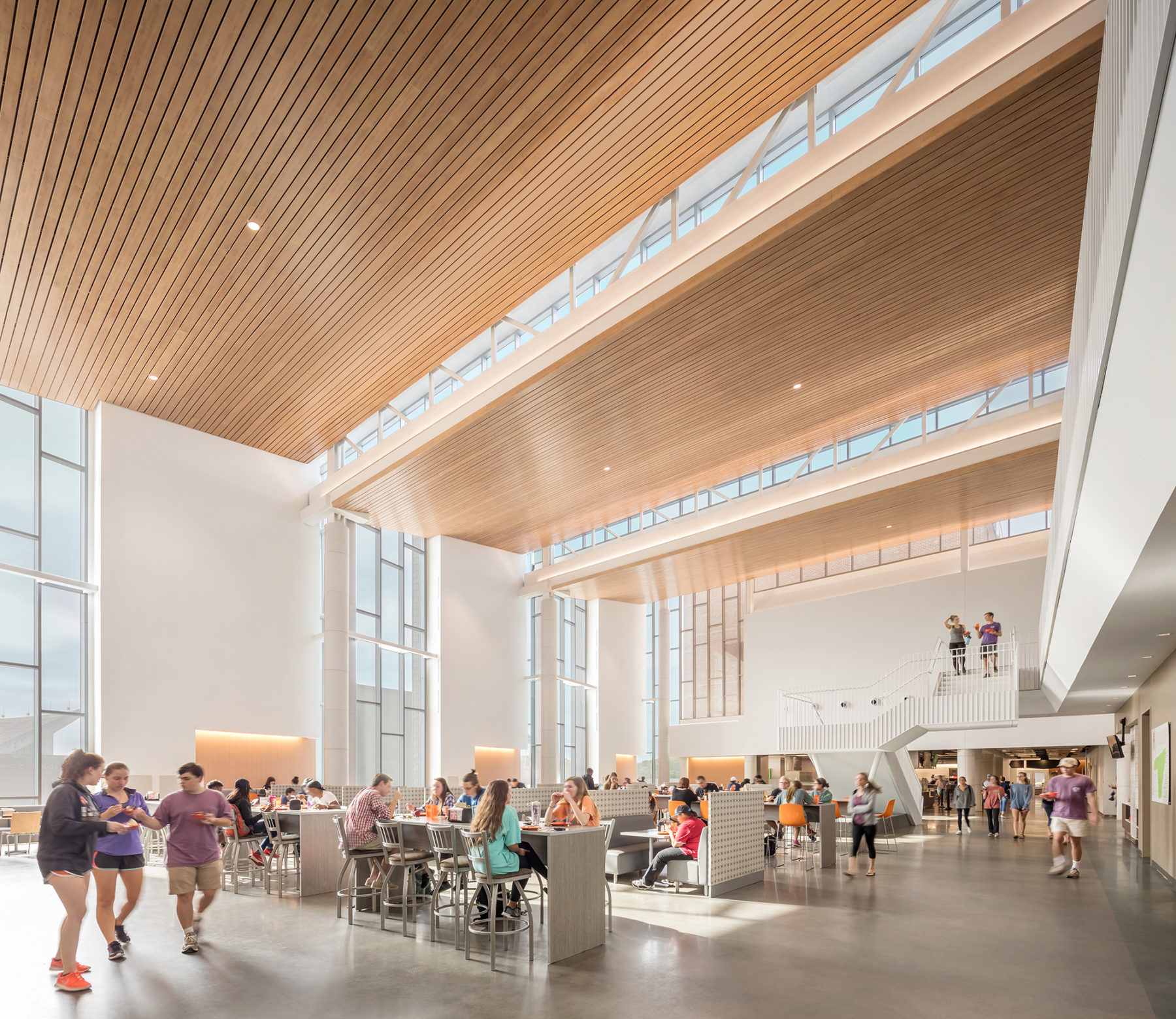 Students eating in a large dining hall with large wooden panels overhead