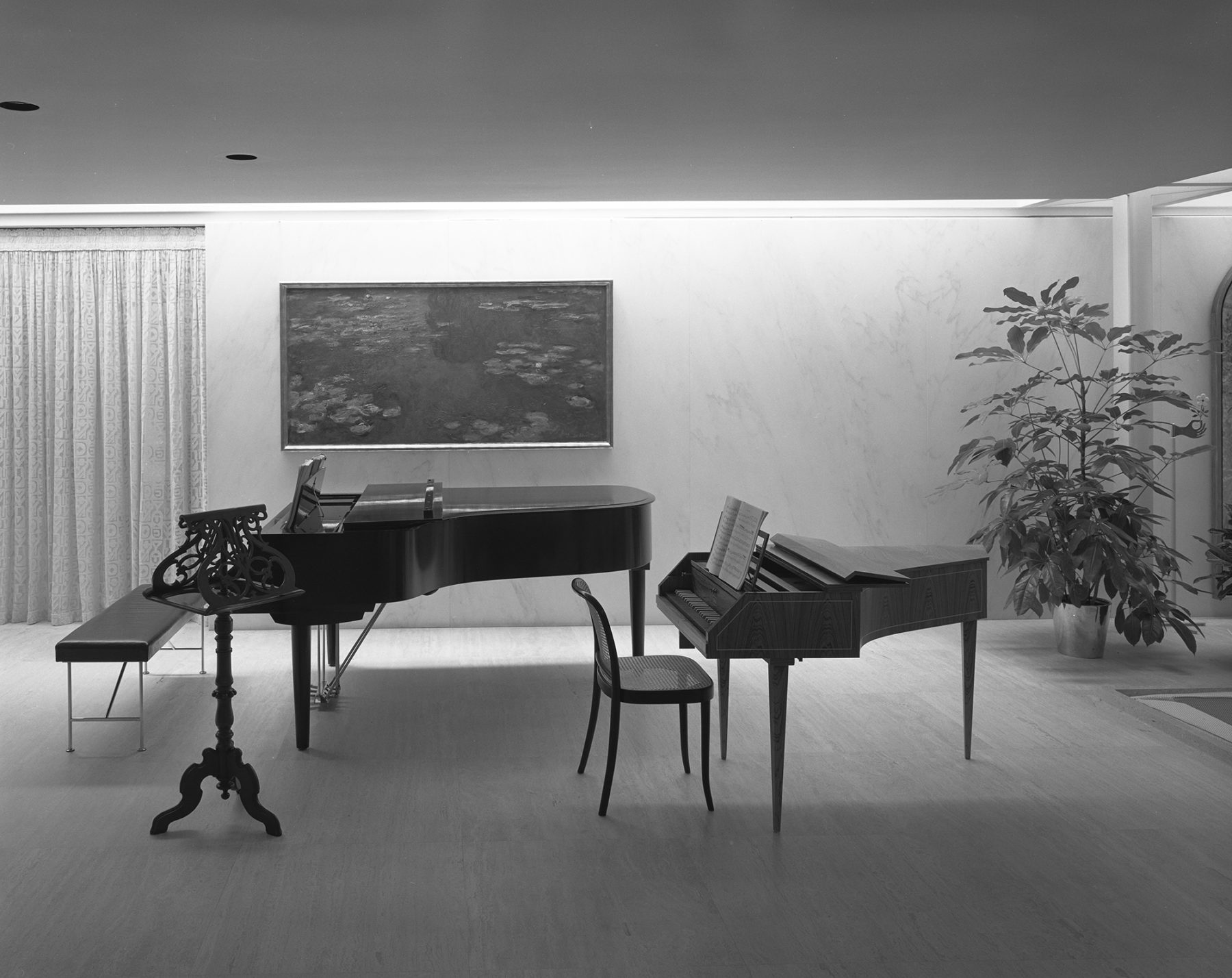 Black and white photograph of a grand piano and baby grand piano