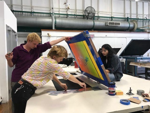 three art students setting up a print