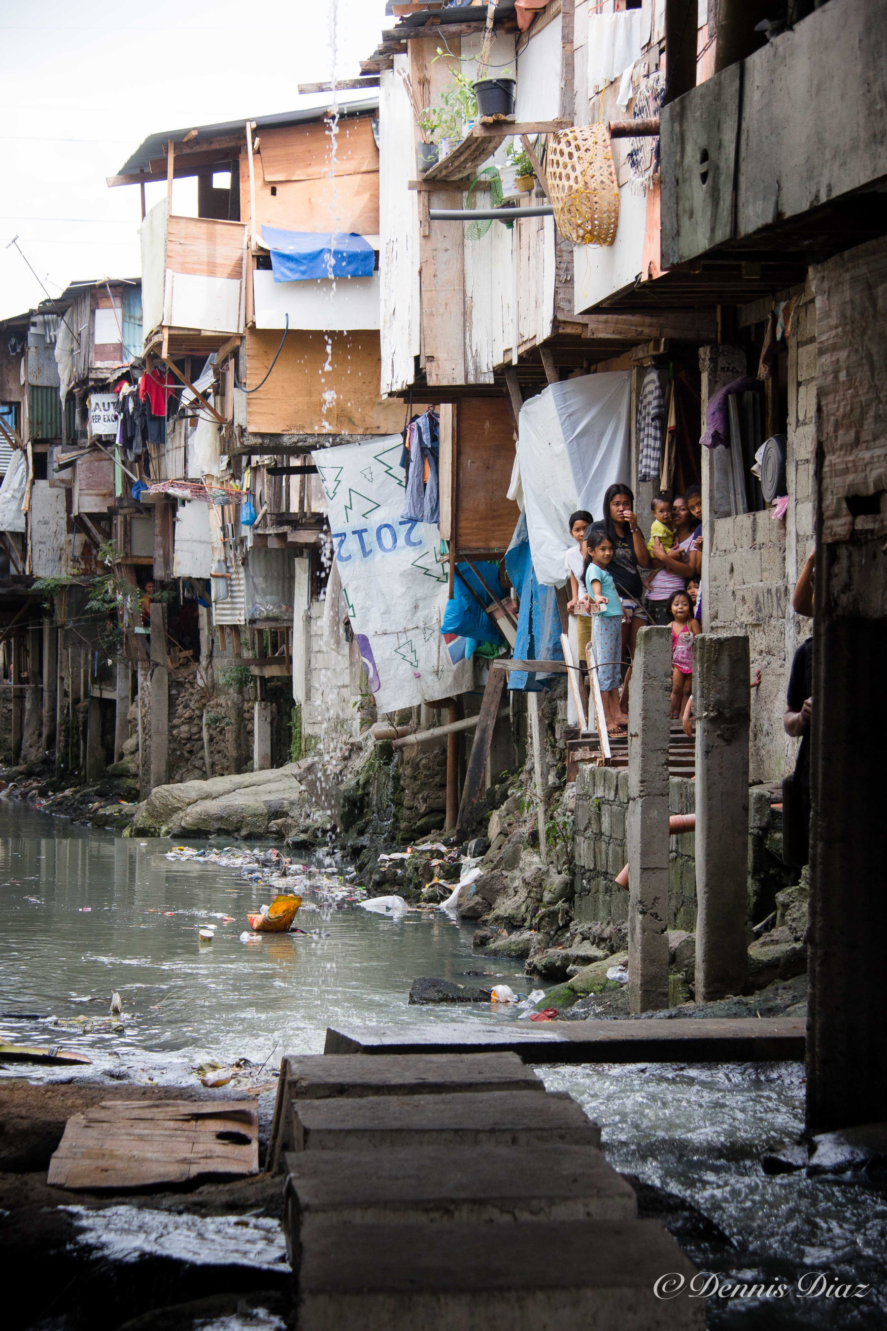 Group of people standing in front of pilapils, informal settlements