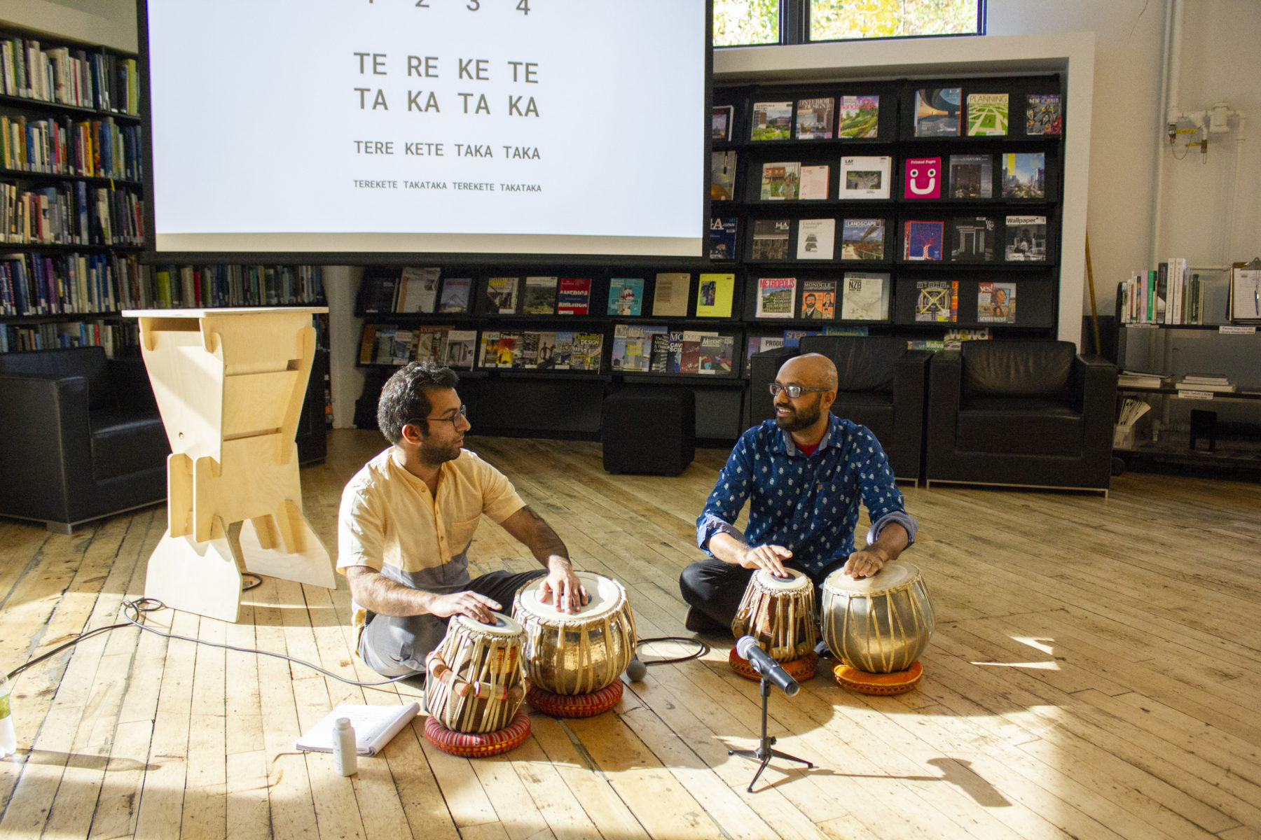 two people sitting on the floor playing tablas