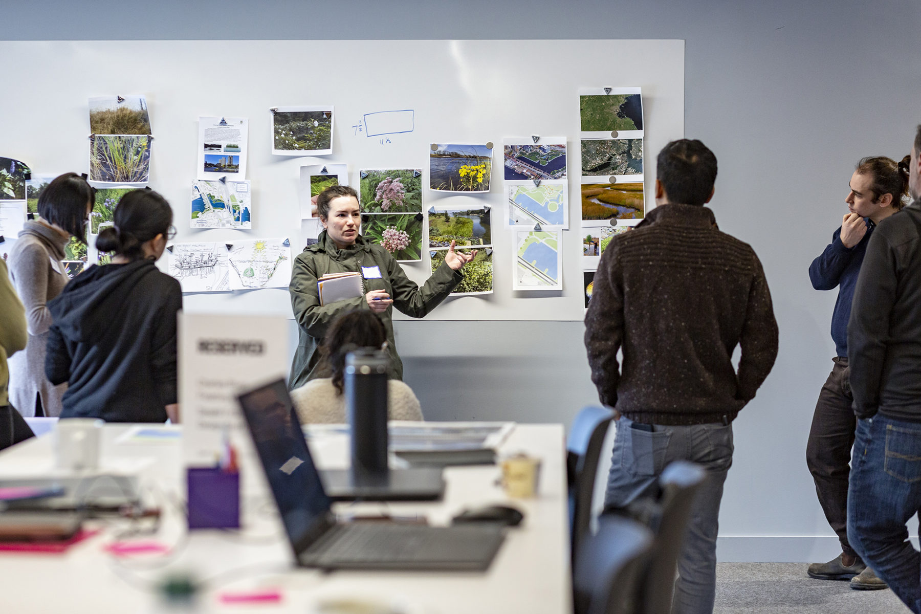 Photo of woman leading a discussion pointing to images on a whiteboard