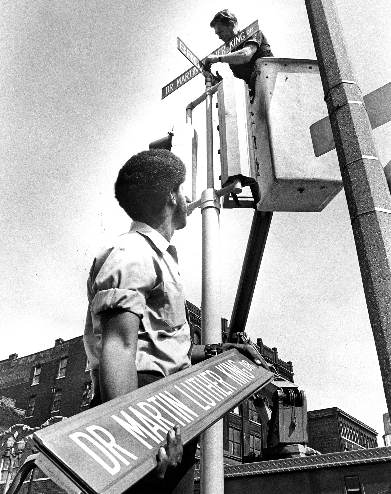 historic photo of two people changing street signs