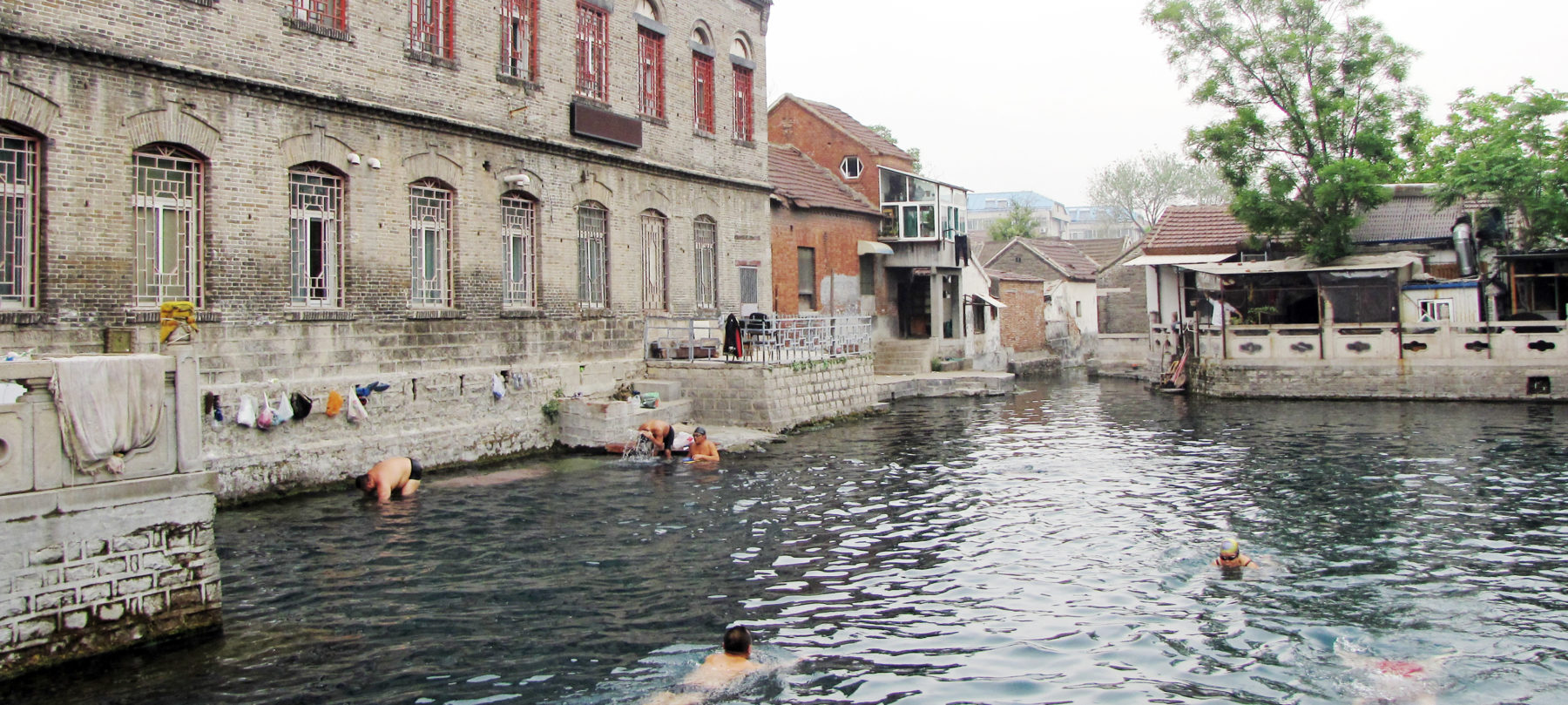 People swimming in large body of water in urban setting