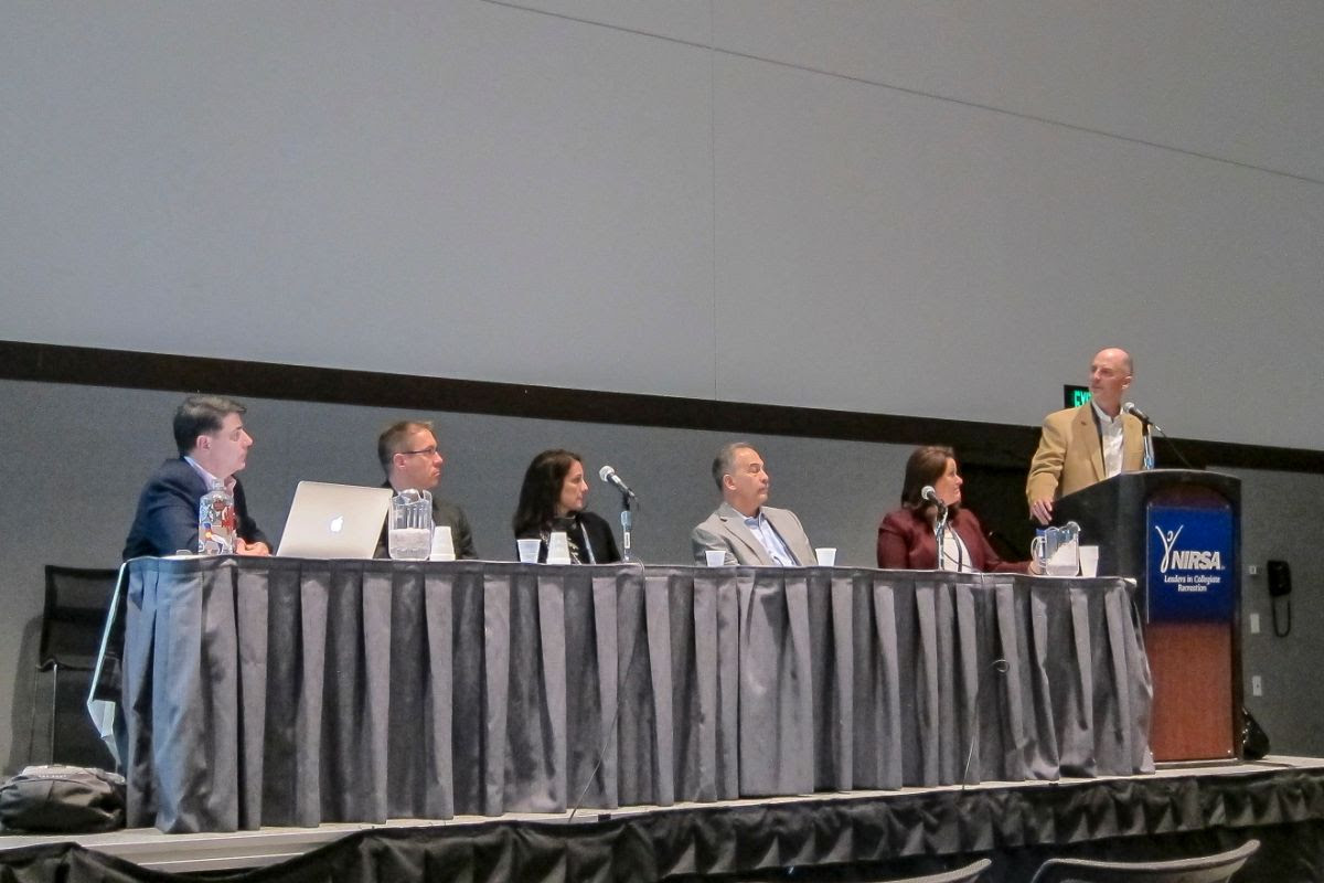 Sgarzi speaking at podium next to panel of speakers