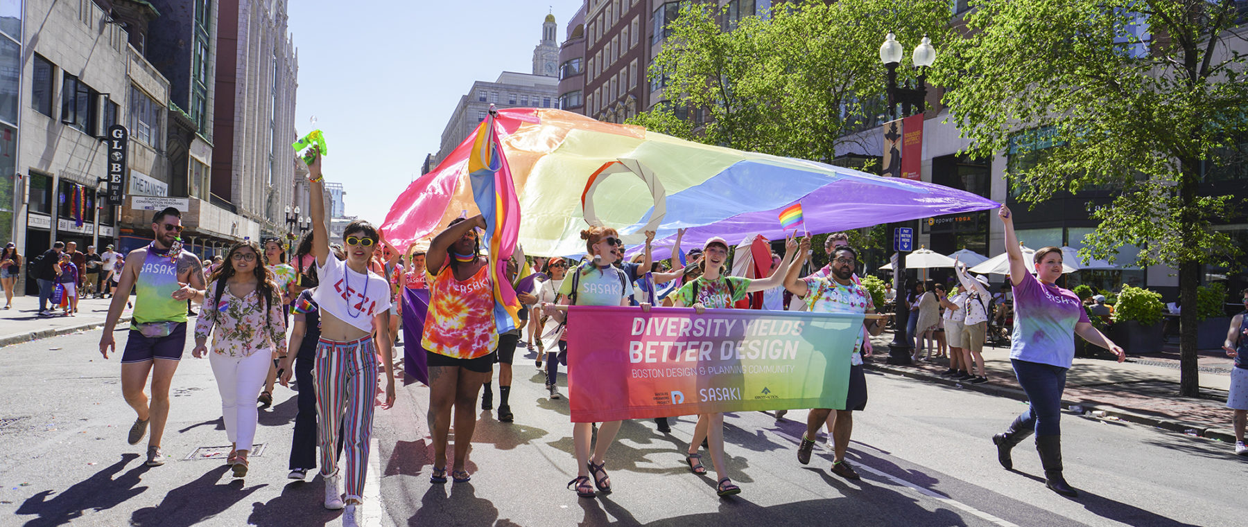 Group marching in Pride parade with banner and flag waving overhead
