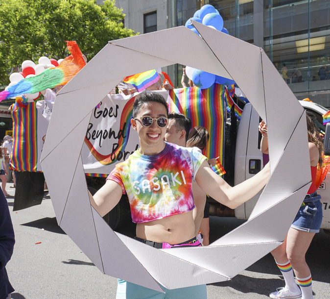 Photo of man wearing tie-dyed shirt and holding large cardboard parade prop