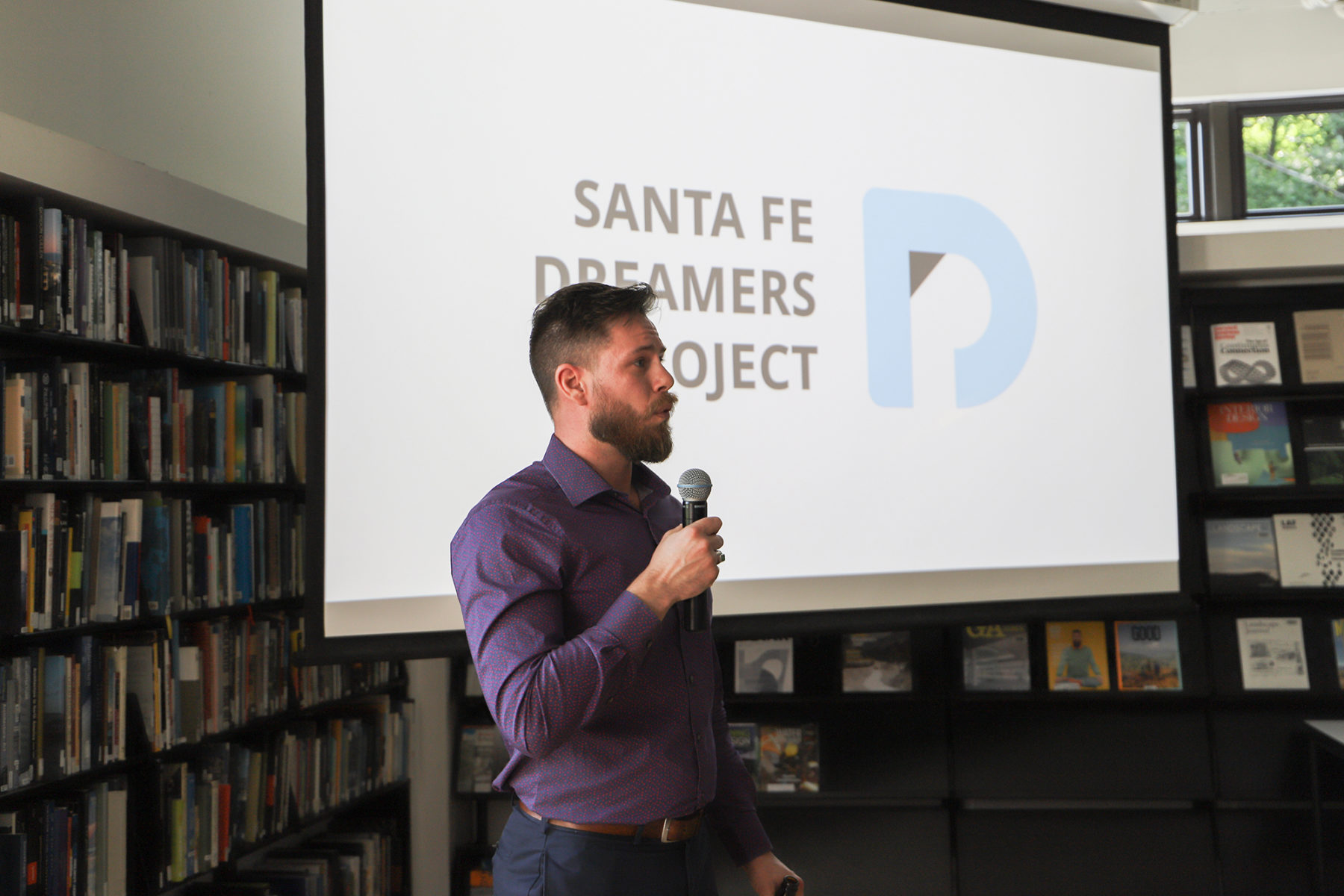 Man speaking to group in front of screen with Santa Fe Dreamers Project logo