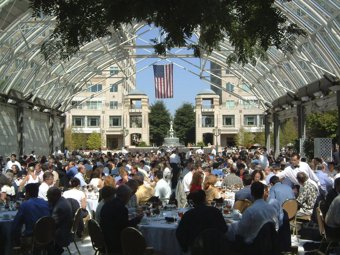 an crowed gathered at tables under an outdoor structure
