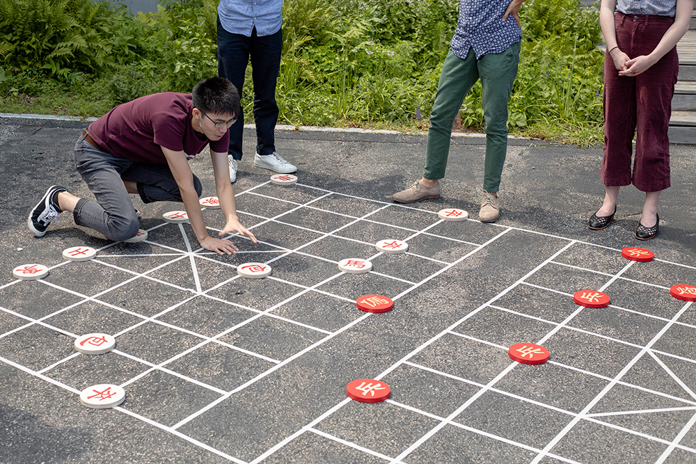 person playing over-sized game of Chinese checkers on pavement