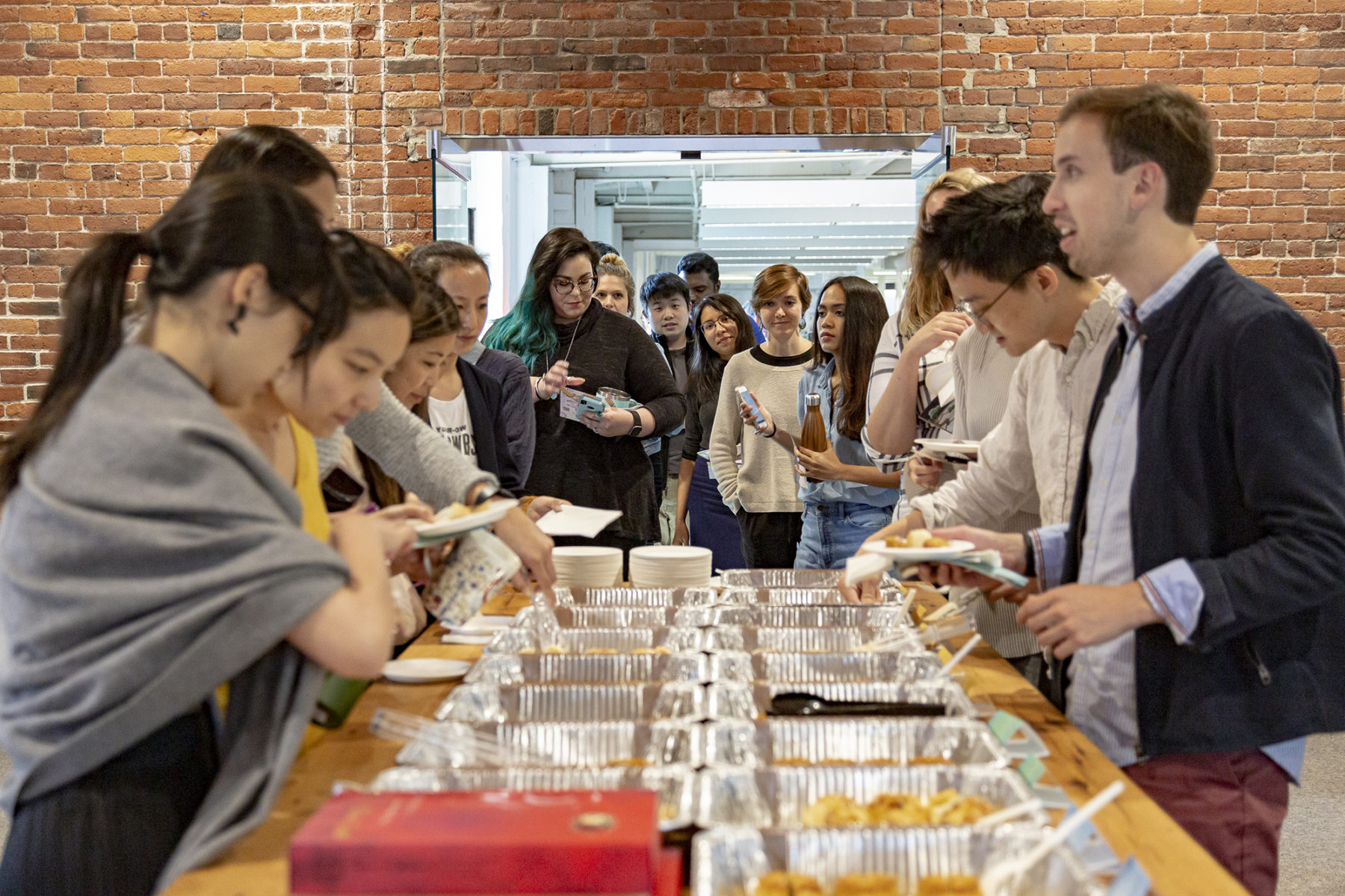 Photo of people gathering around a table of food