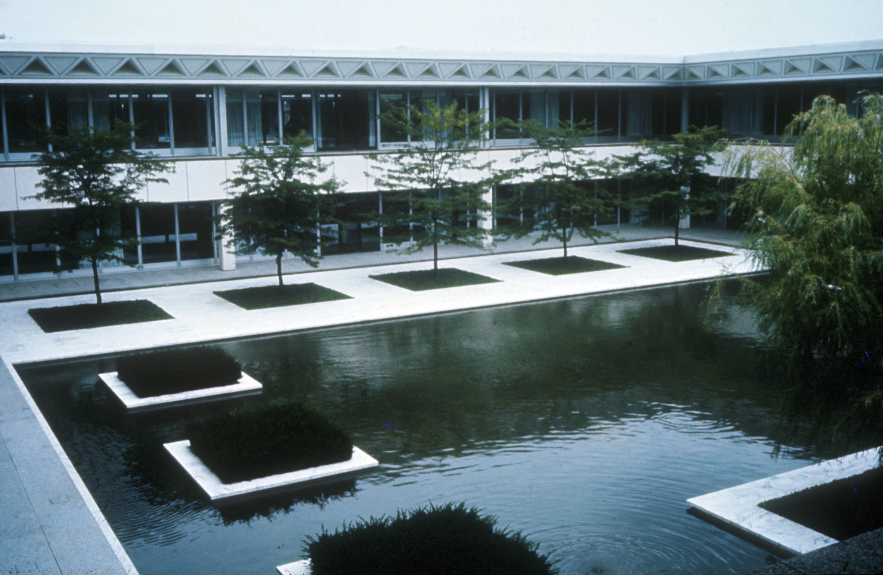 photograph of reflecting pool in courtyard enclosed by two-story office buildings and featuring floating planters