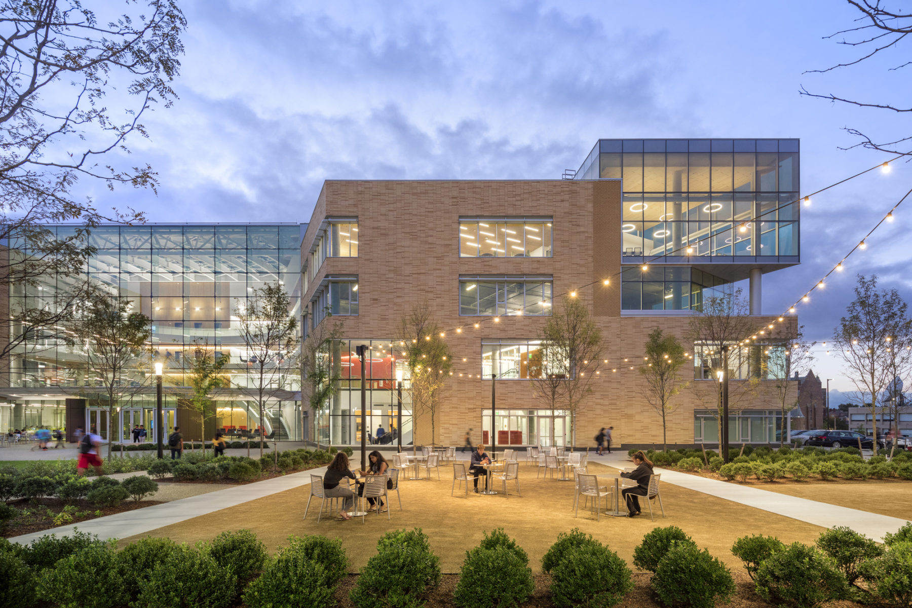 Photograph of exterior view of Tepper Quadrangle with people sitting.