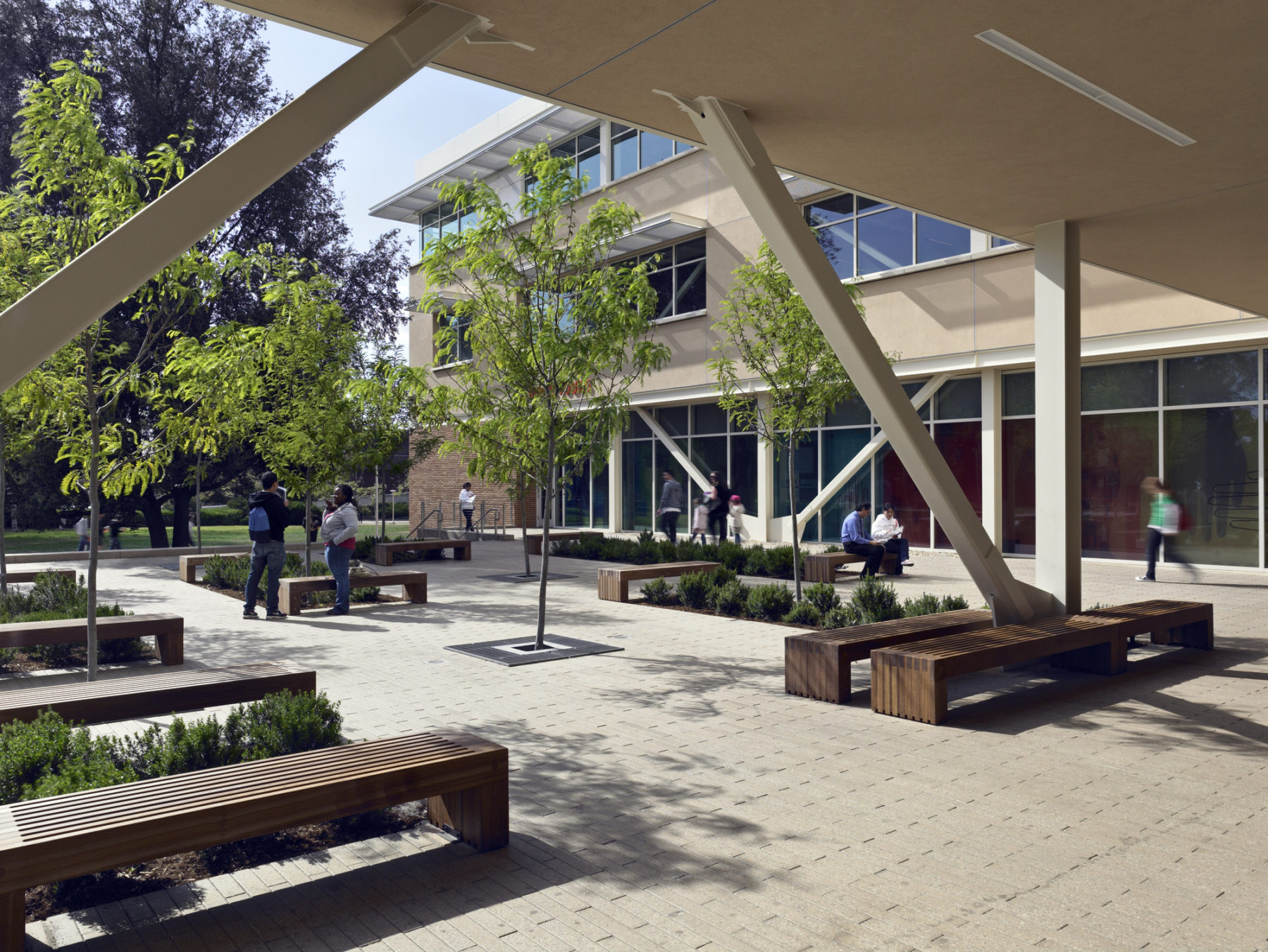 Exterior photo of plaza adjacent to building. Students sit on benches.