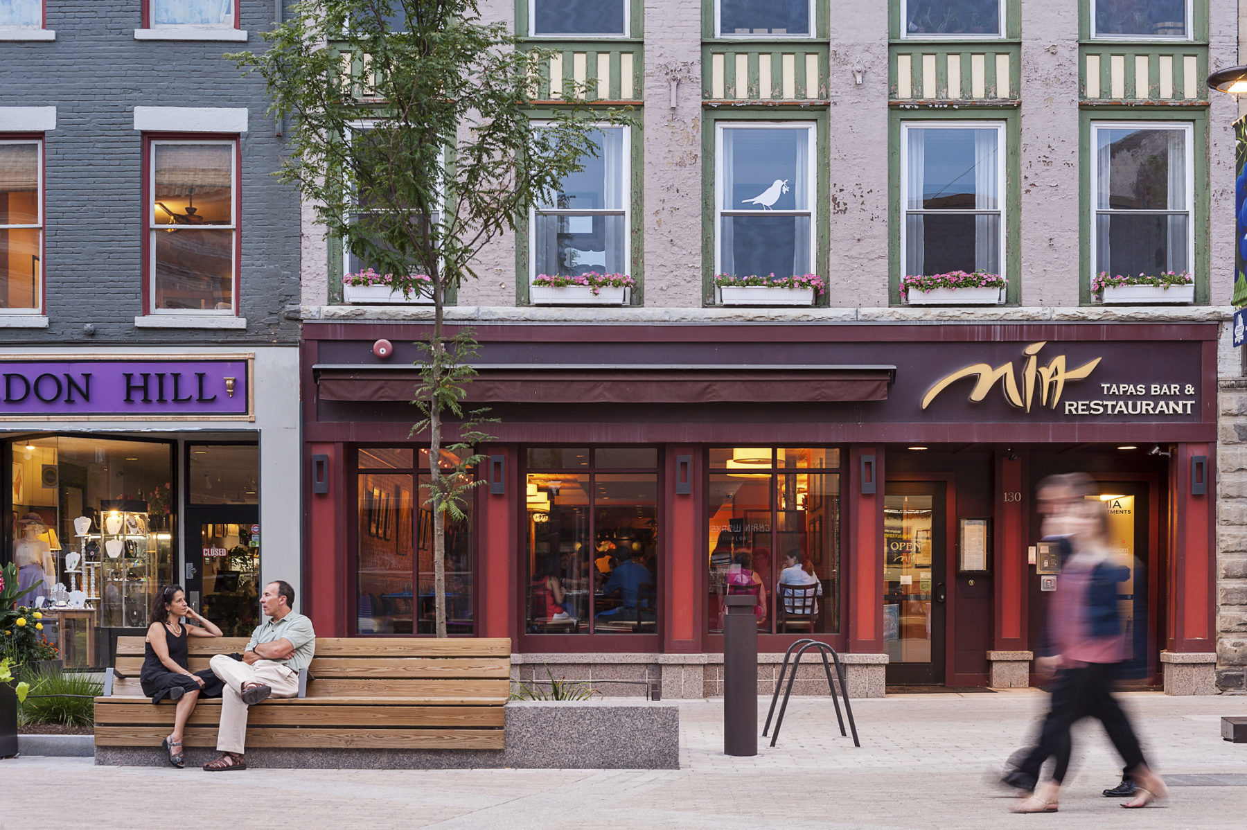 People talking on a wooden bench outside of a local restaurant