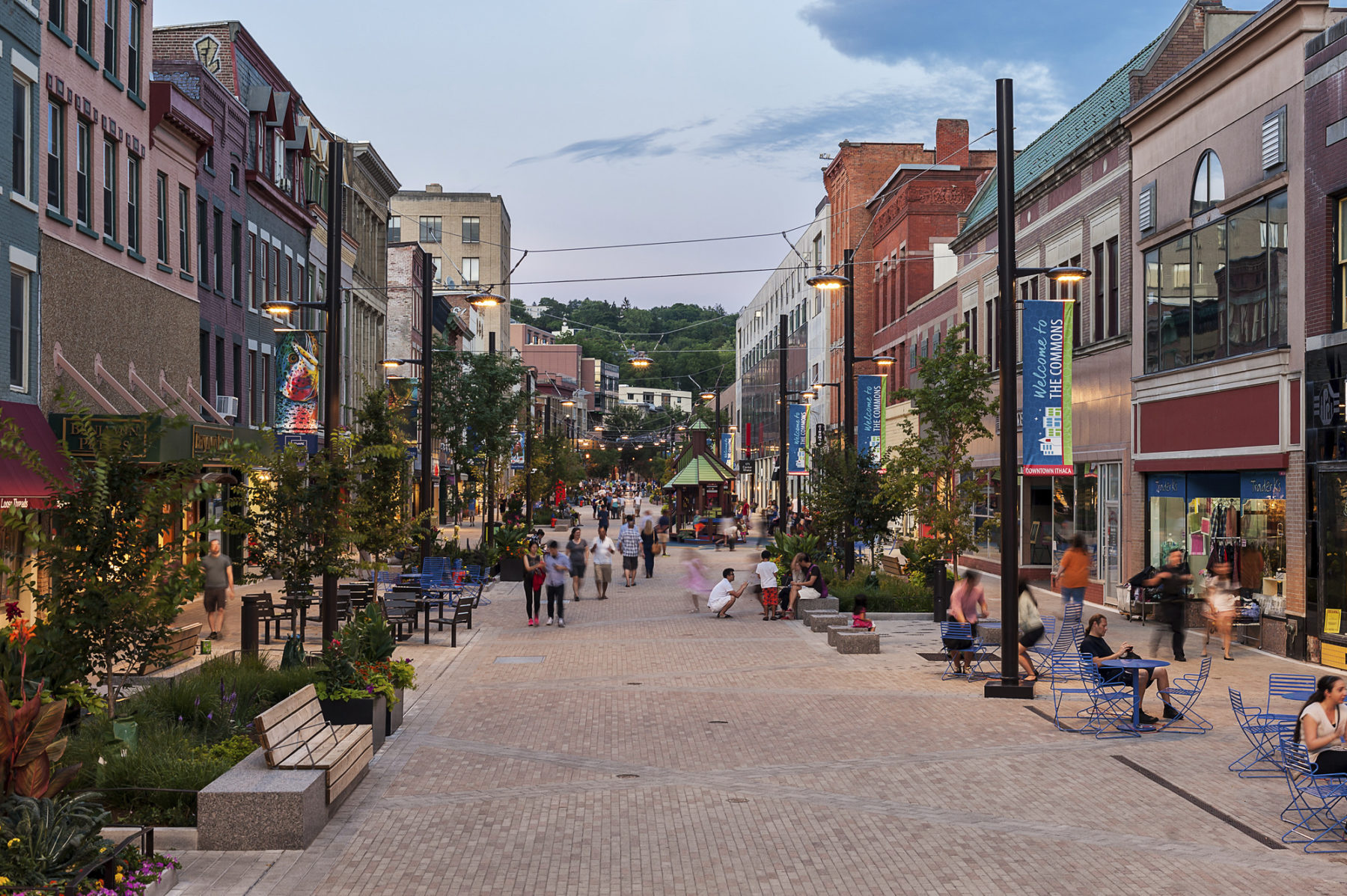 Evening view of a populated street with storefronts on either side