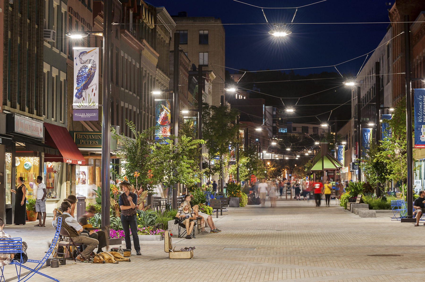 Street performers and pedestrians utilize the walking space of the pedestrian mall