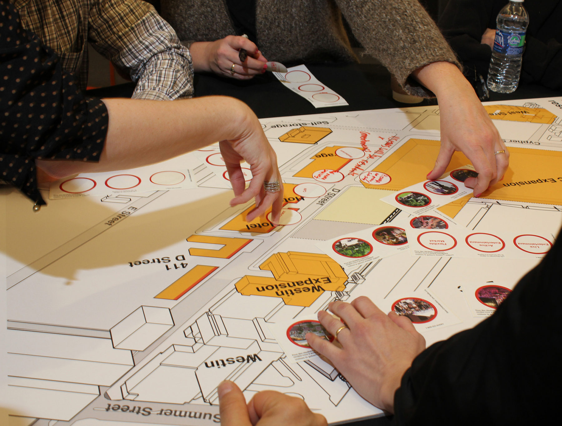 Photograph of people's hands moving program elements around on drawing