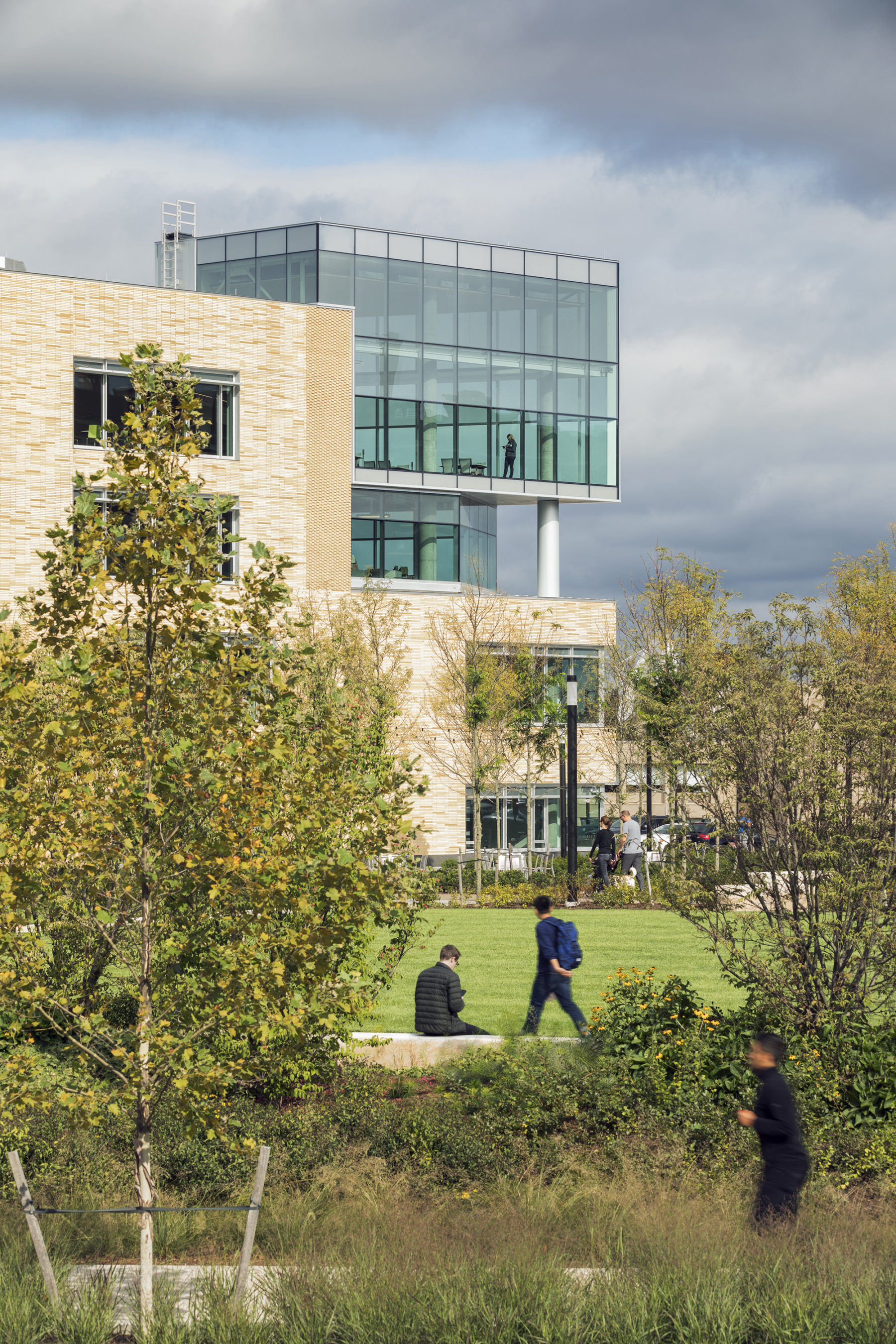 Exterior view of building lined with trees and perennials.