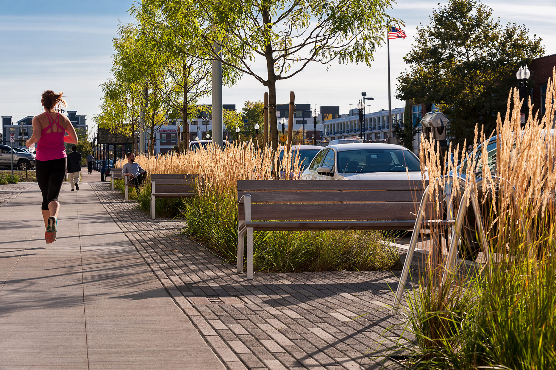 Photo of the benches along the corridor. A woman jogs on the sidewalk.