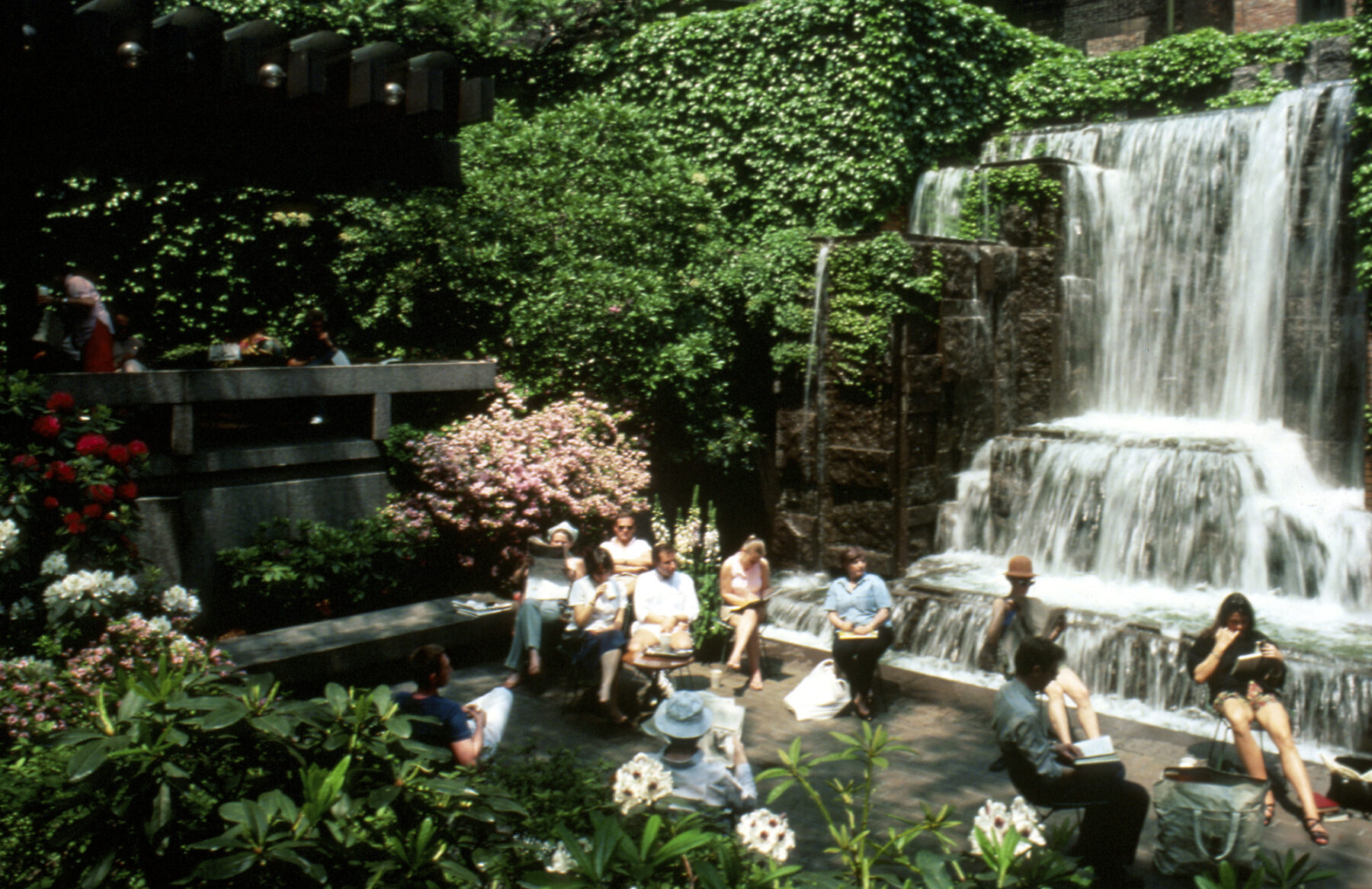 Aged photo of park with visitors enjoying seating beside the waterfall