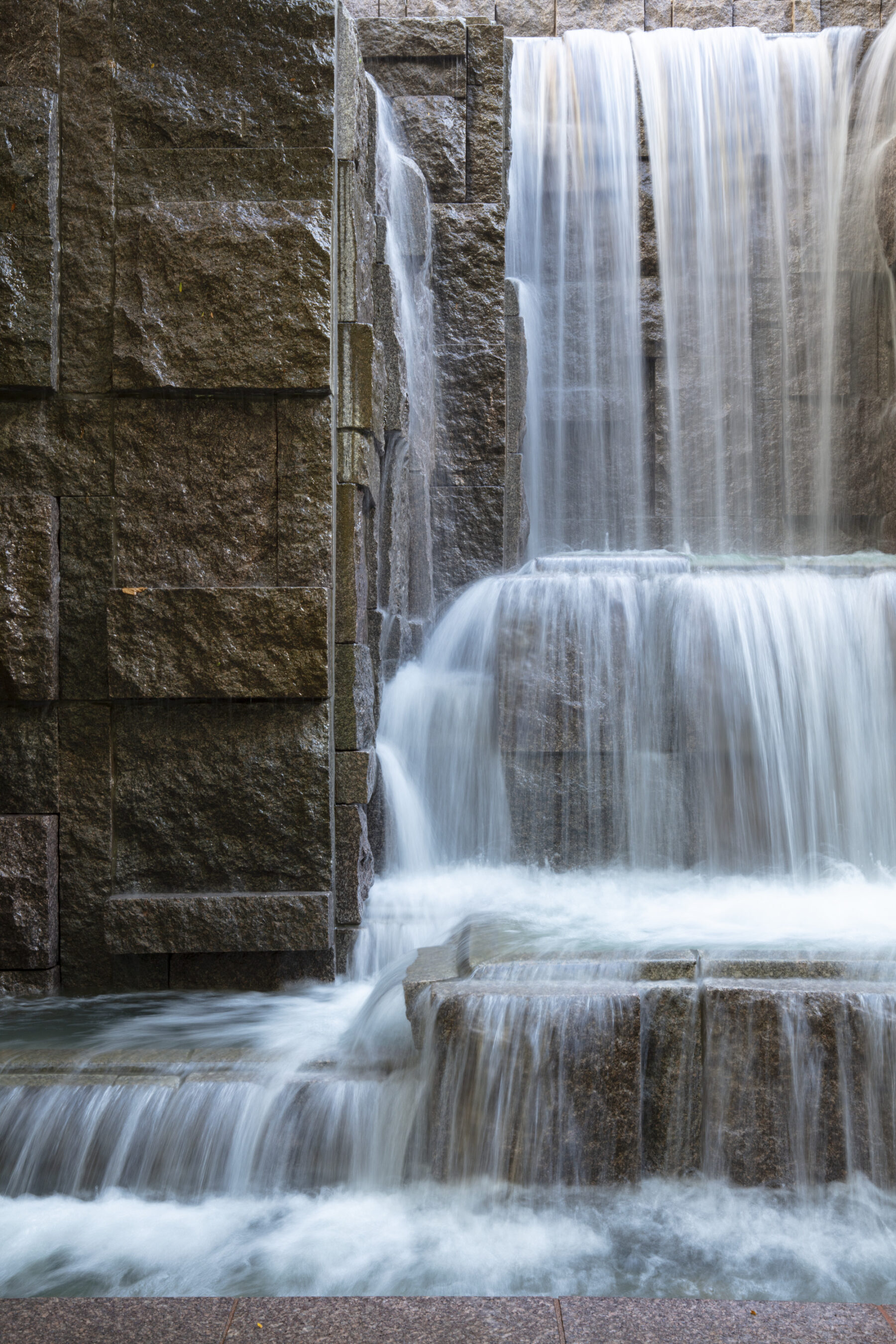 Close up photo of waterfall with three tiers and detail of stone materials