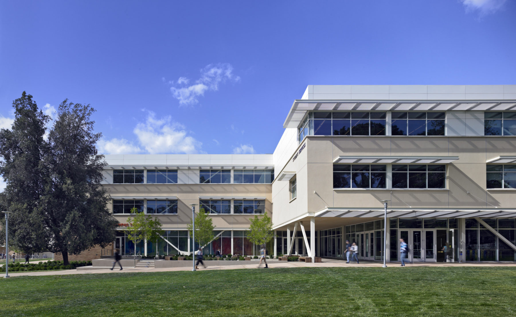 Exterior photo of building on a sunny day. Students walk along the path in front of the building