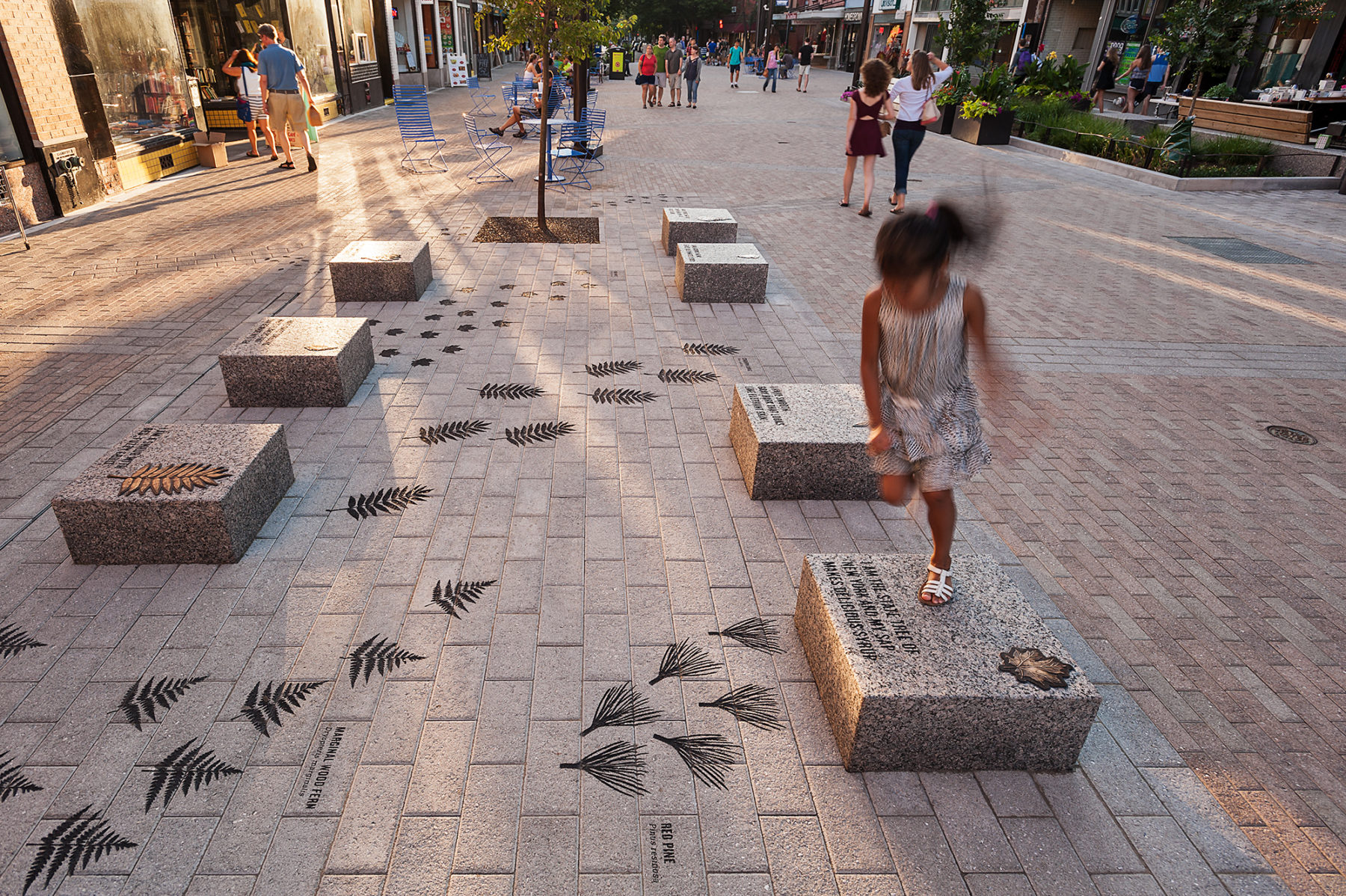 Child plays on the stone seats painted with tree symbols