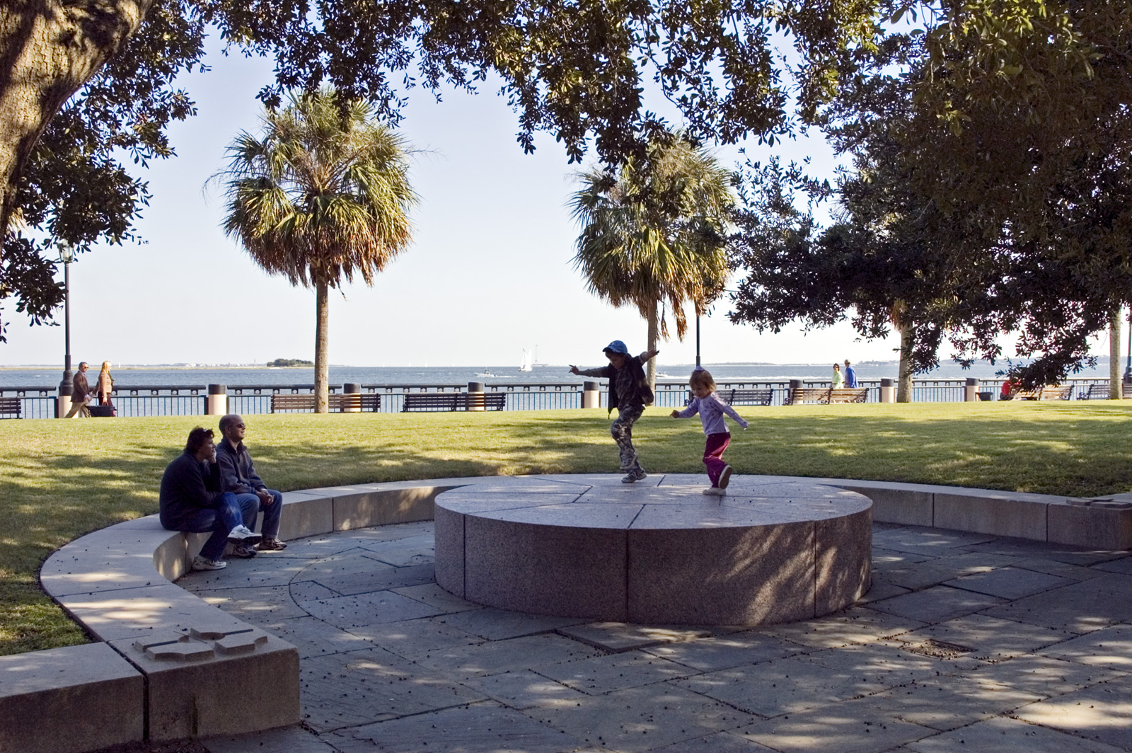Photo of children jumping on stone ledge in park