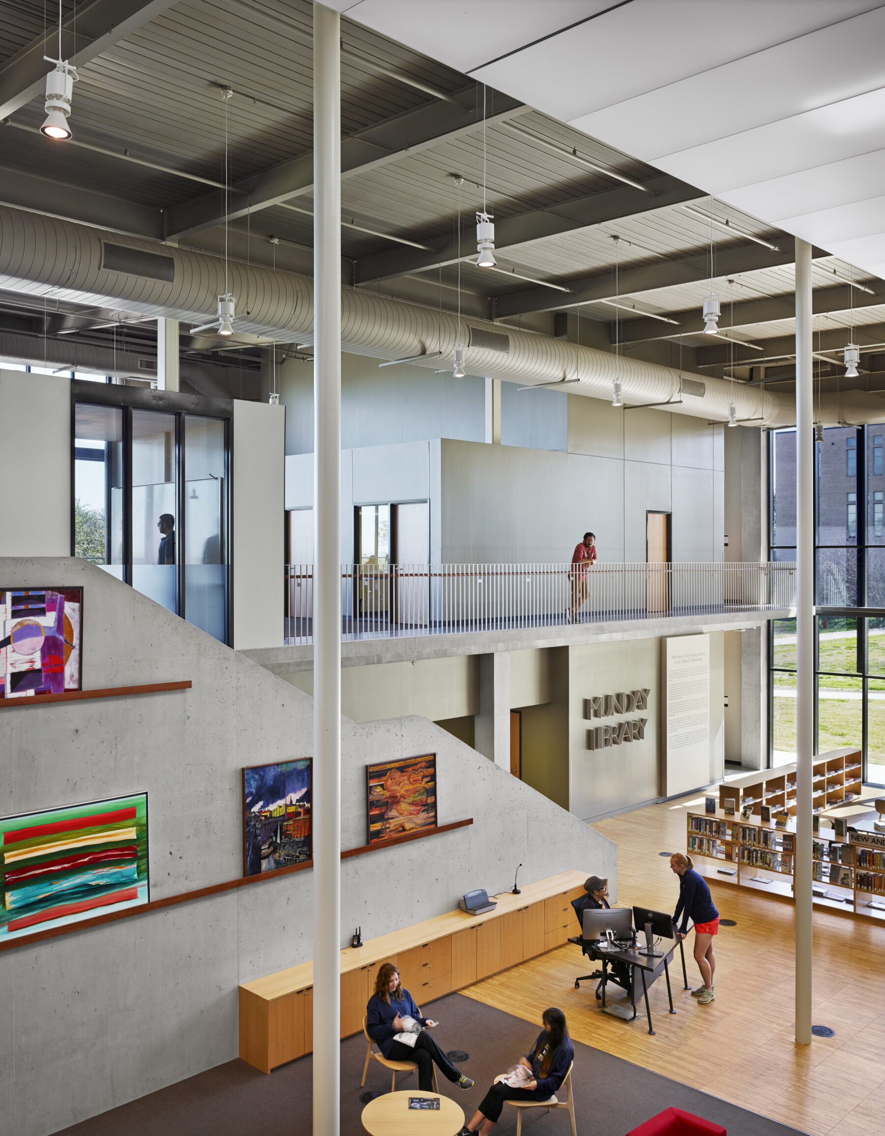 perspective shot of interior library featuring display art and concrete walls