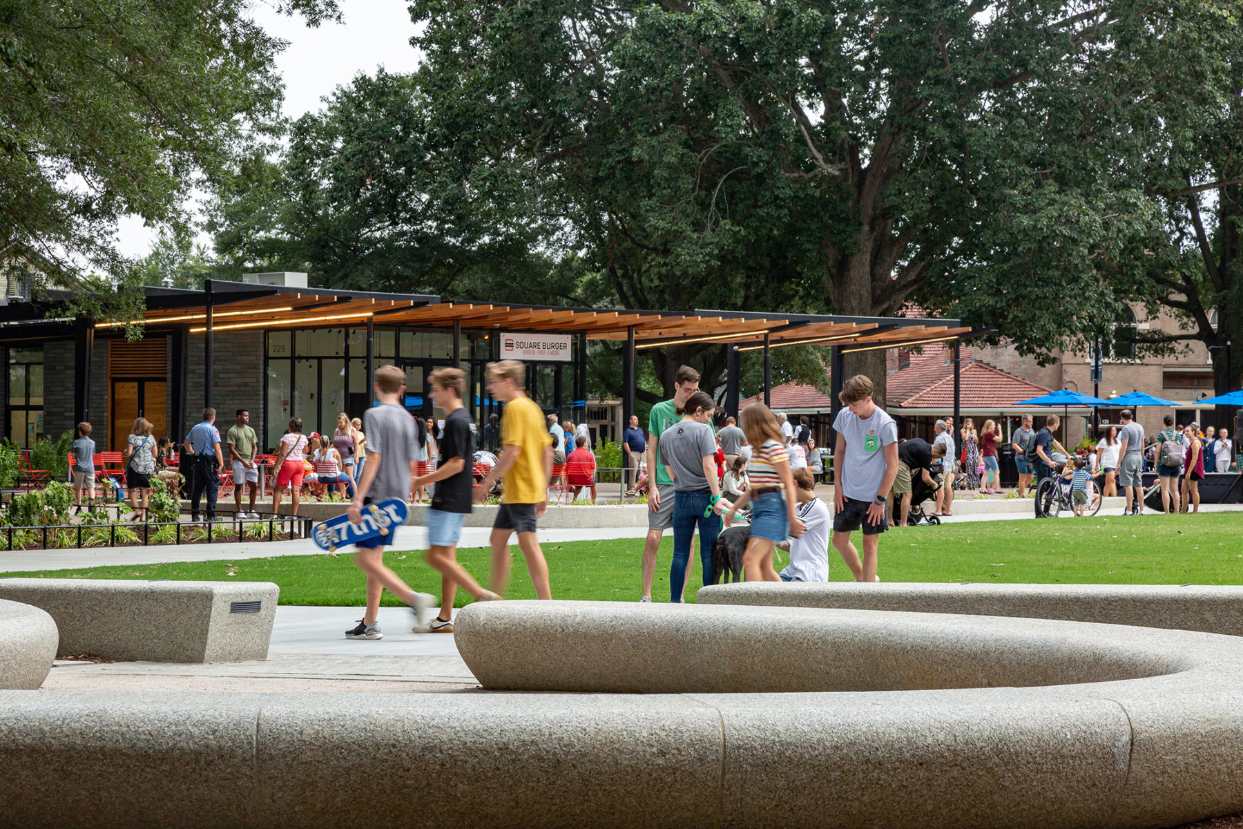 photo of park with lots of people, stone seating elements in foreground