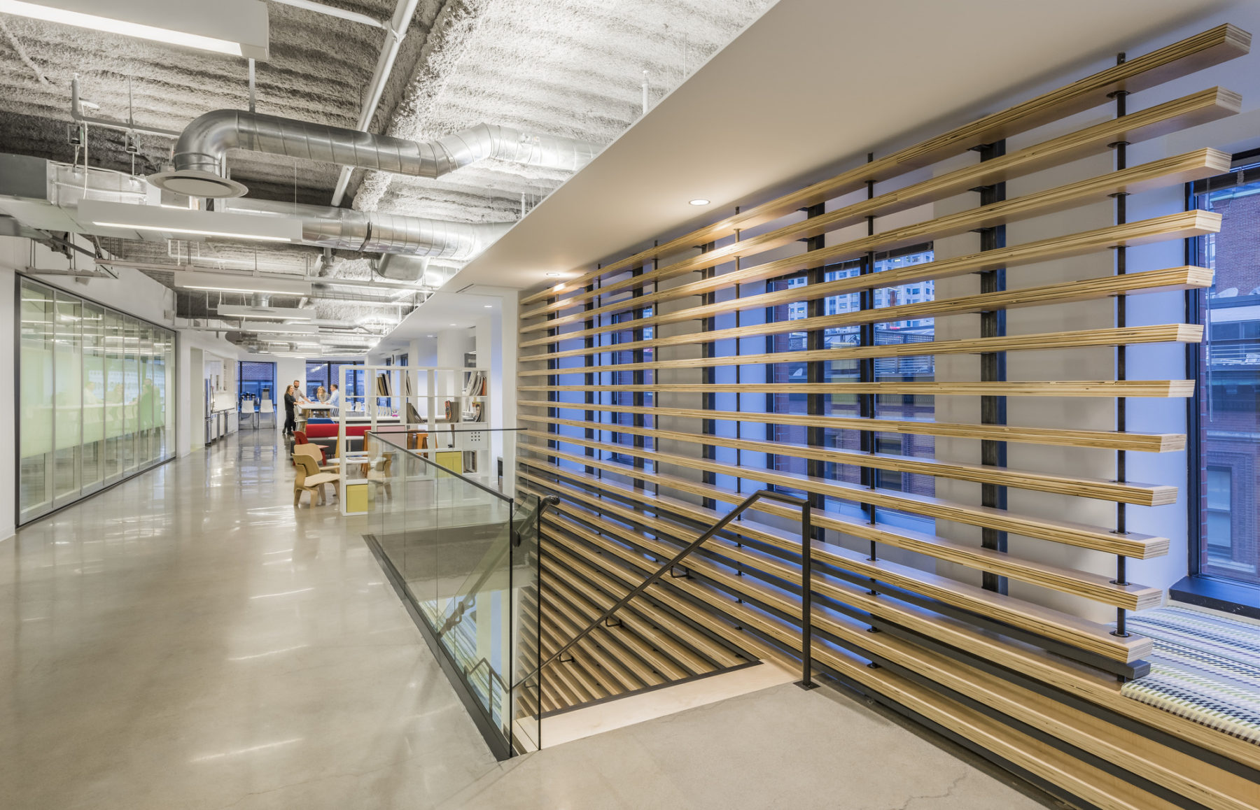 Open office area with stairs leading down. Windows by the stairs decorated with lines of long wooden blocks.