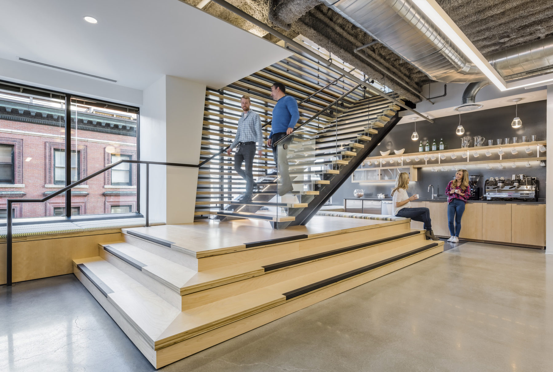 Wooden stairs leading down to the shared communal area with kitchen and sofa set.