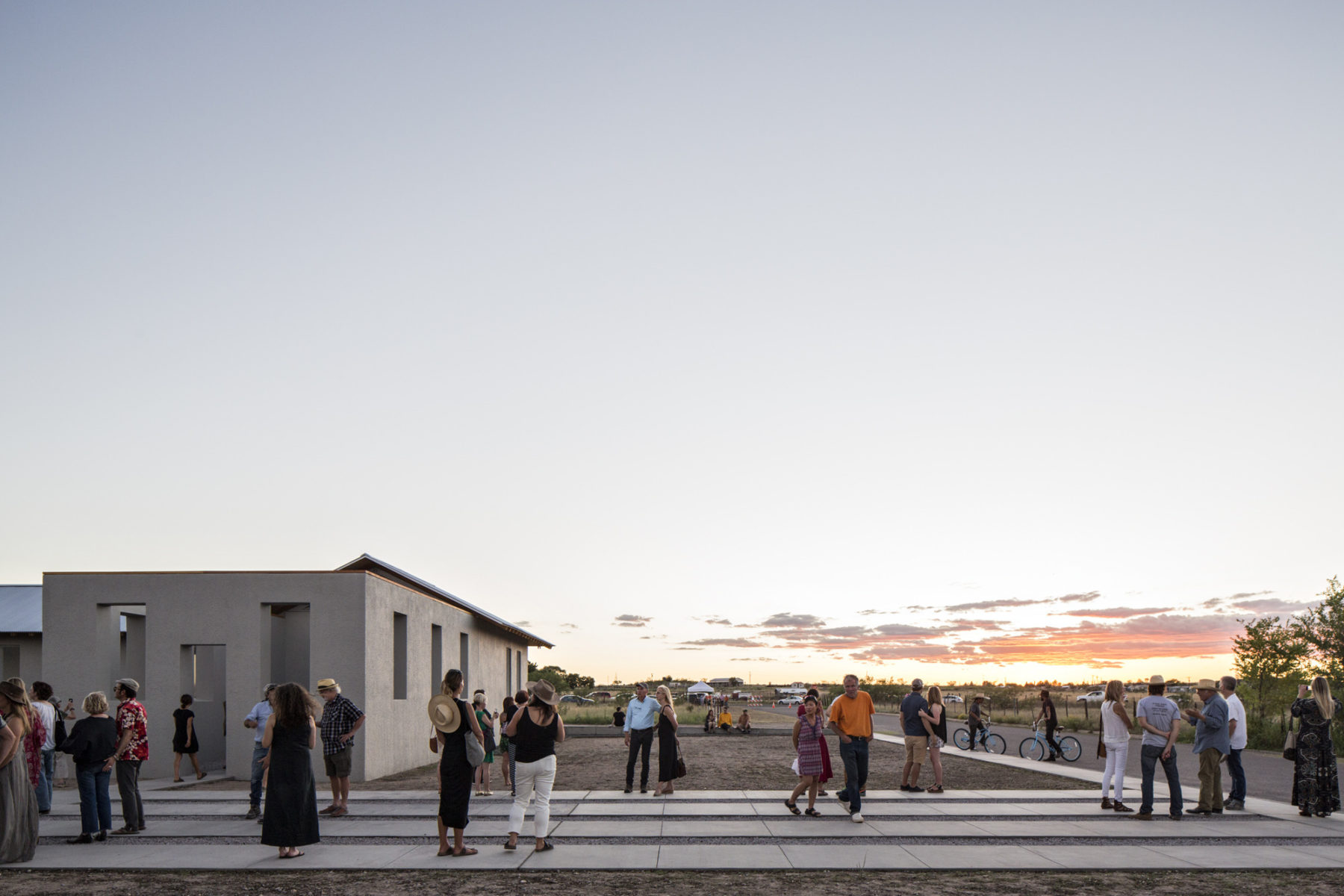 Exterior sunset view of lawn with people gathered outside.