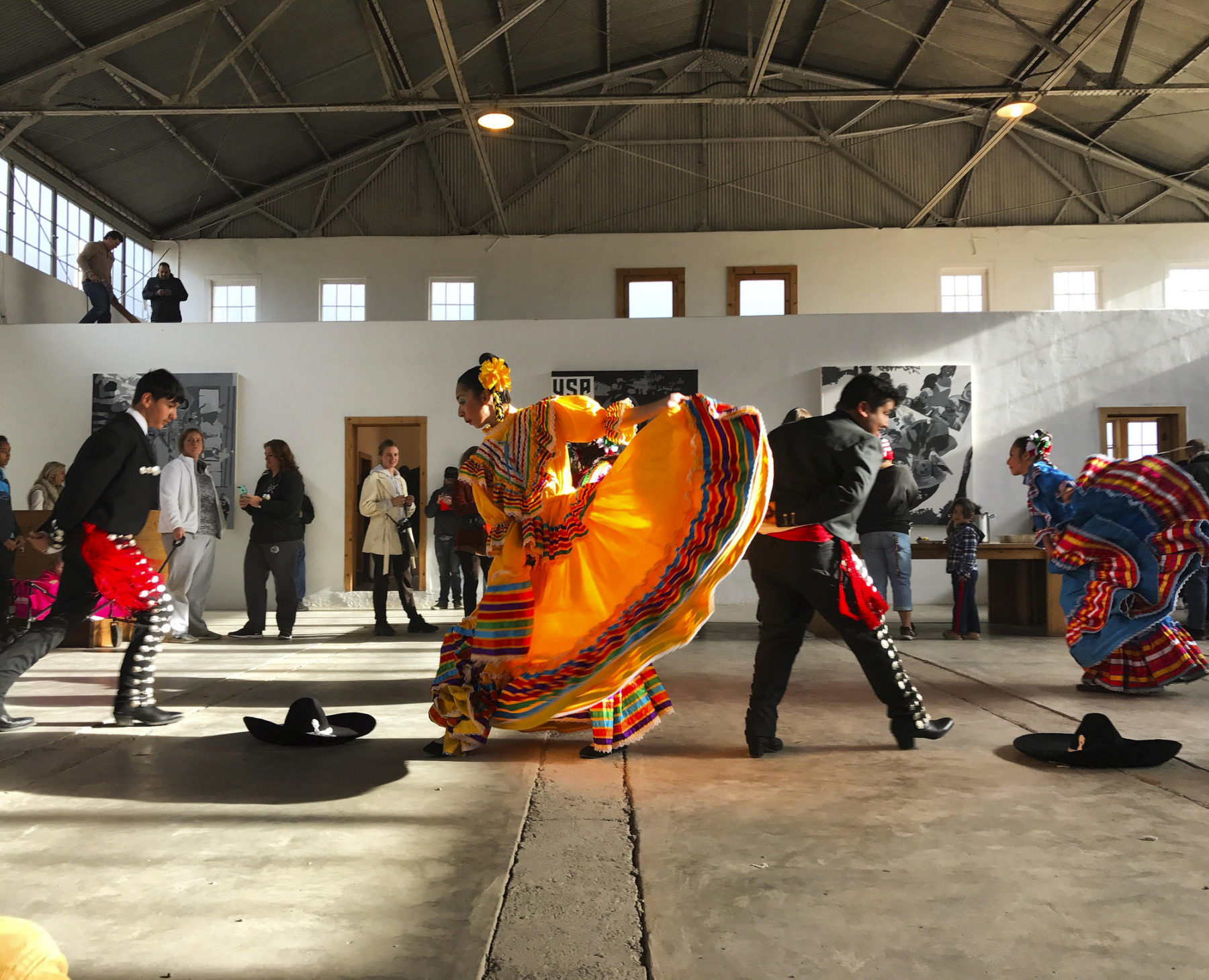 Interior view of artists performing inside, including woman in orange dress.