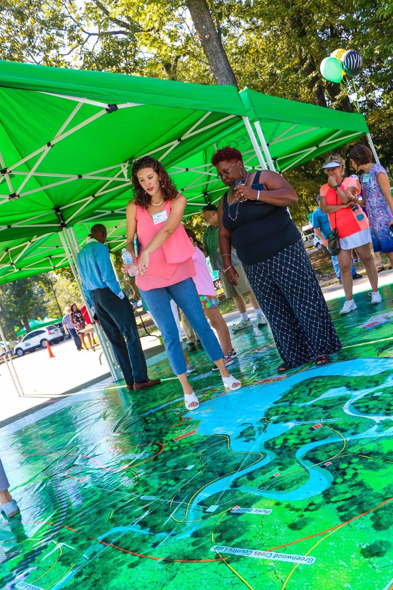 Two people stand on top of a map and point at it