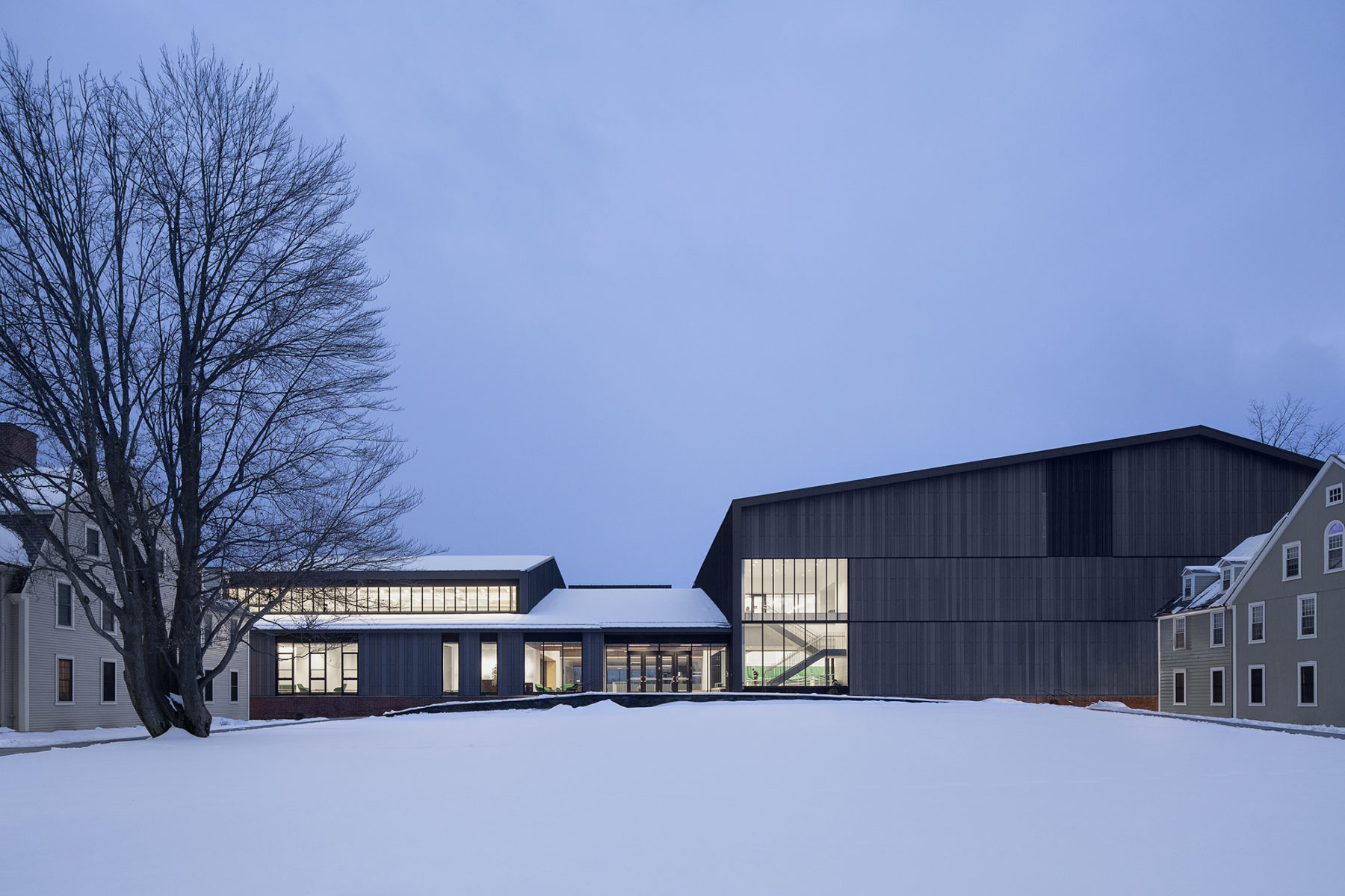 Exterior photo of building illuminated at dusk with snow in foreground