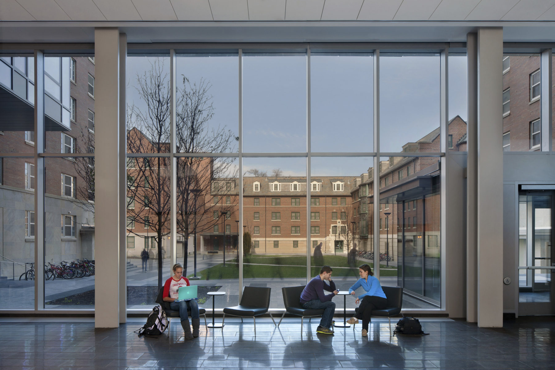 students sitting by large windows inside building