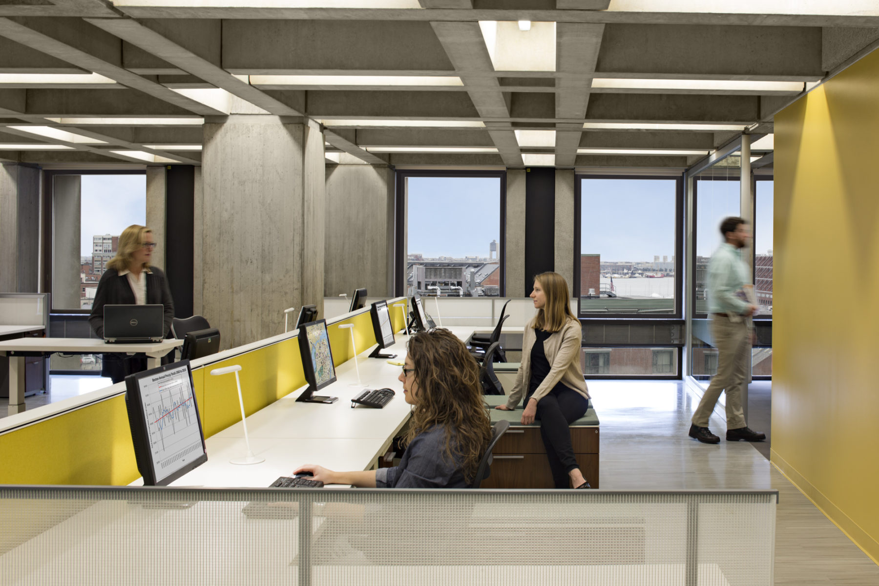 People working at desks and talking over desk divider