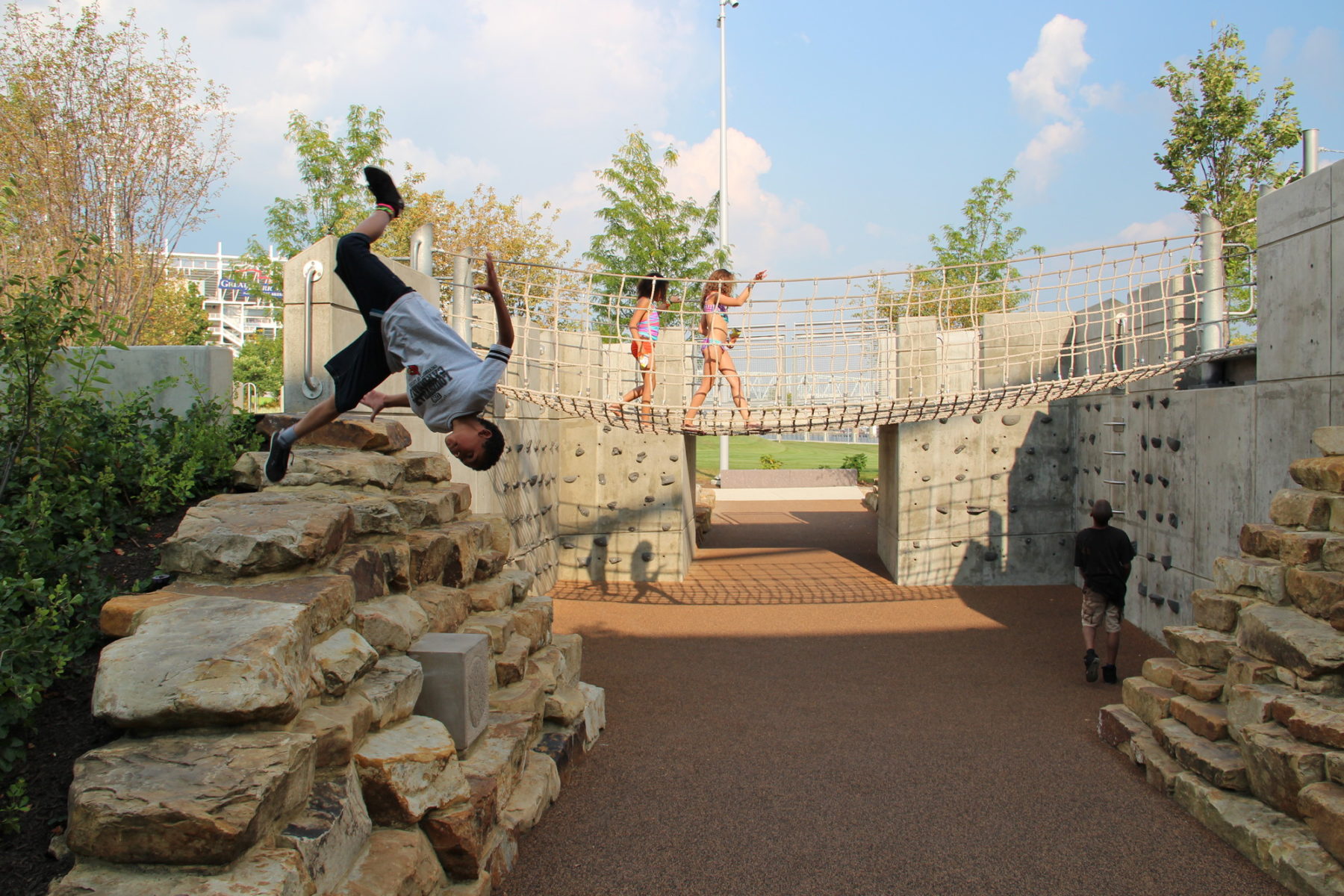 Kid doing a flip off of rock play structure