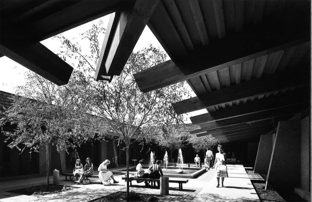 black and white photograph of students around fountain in courtyard space of campus