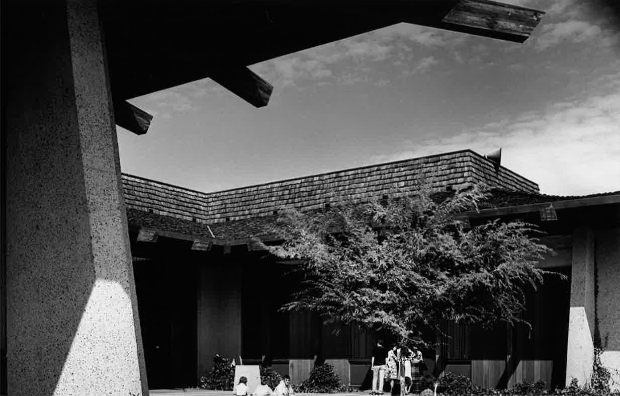 black and white photograph of Foothill College campus featuring students gathered on lawn and underneath tree